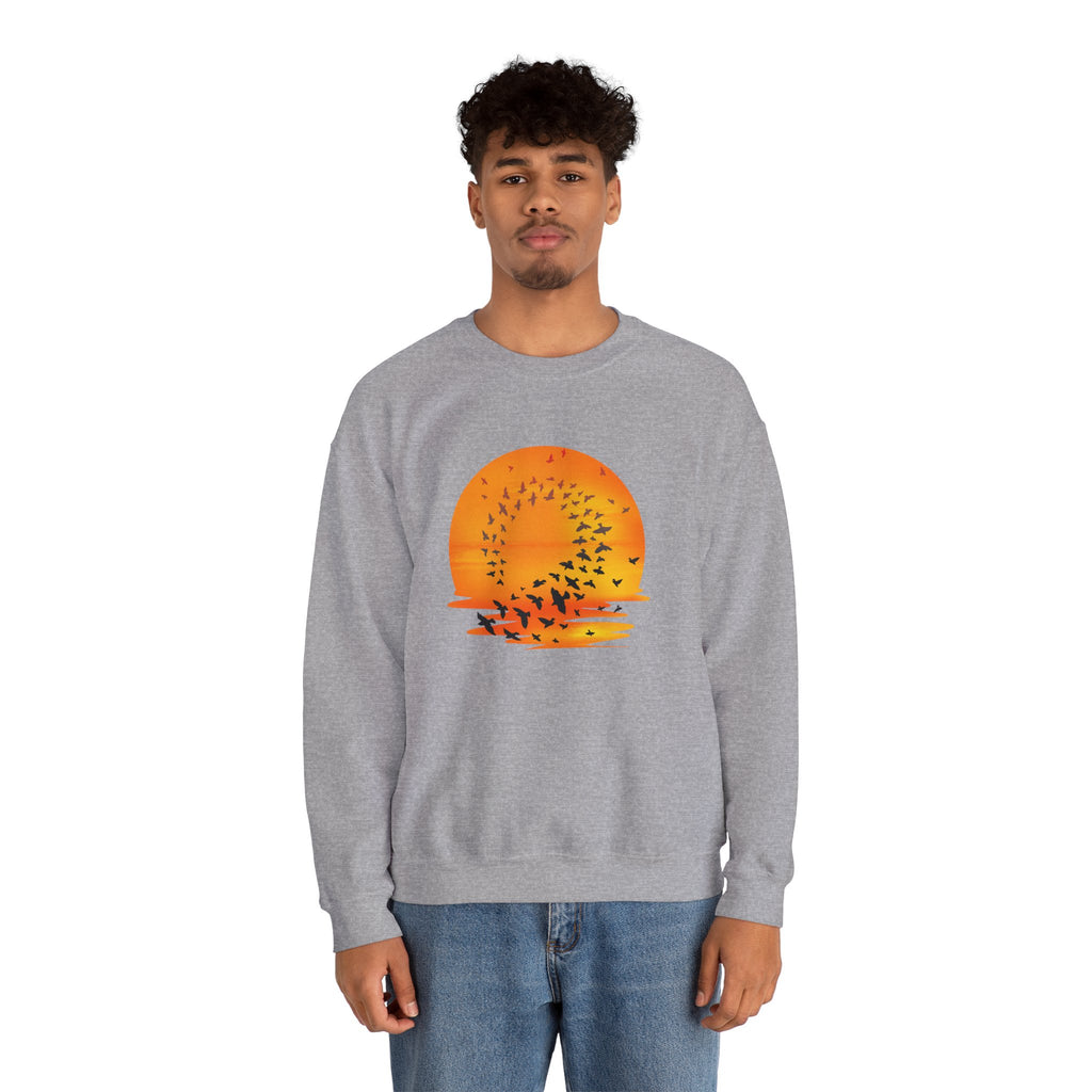 Person wearing a gray sweatshirt with a sunset and bird design on a white background