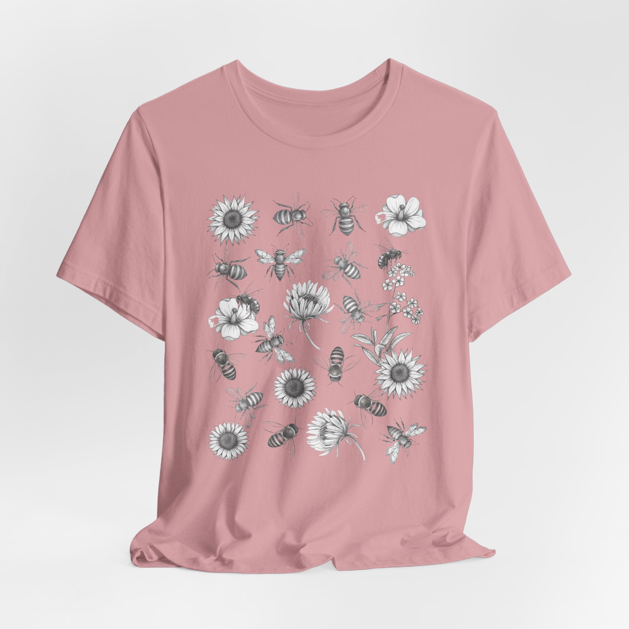 Pink t-shirt with black and white floral and bee design on a light gray background
