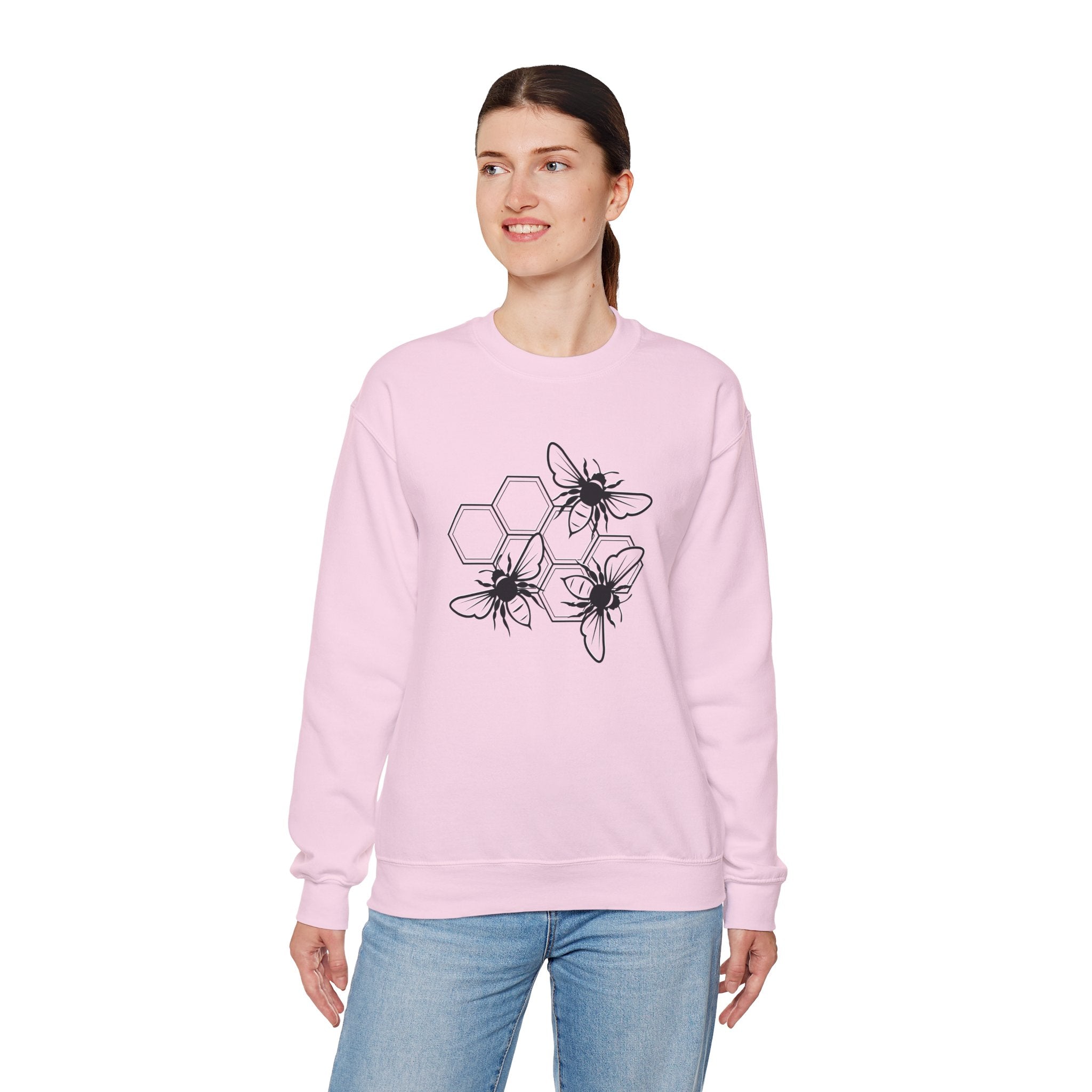 Person wearing a pink sweatshirt with black bee and hexagon pattern on a white background