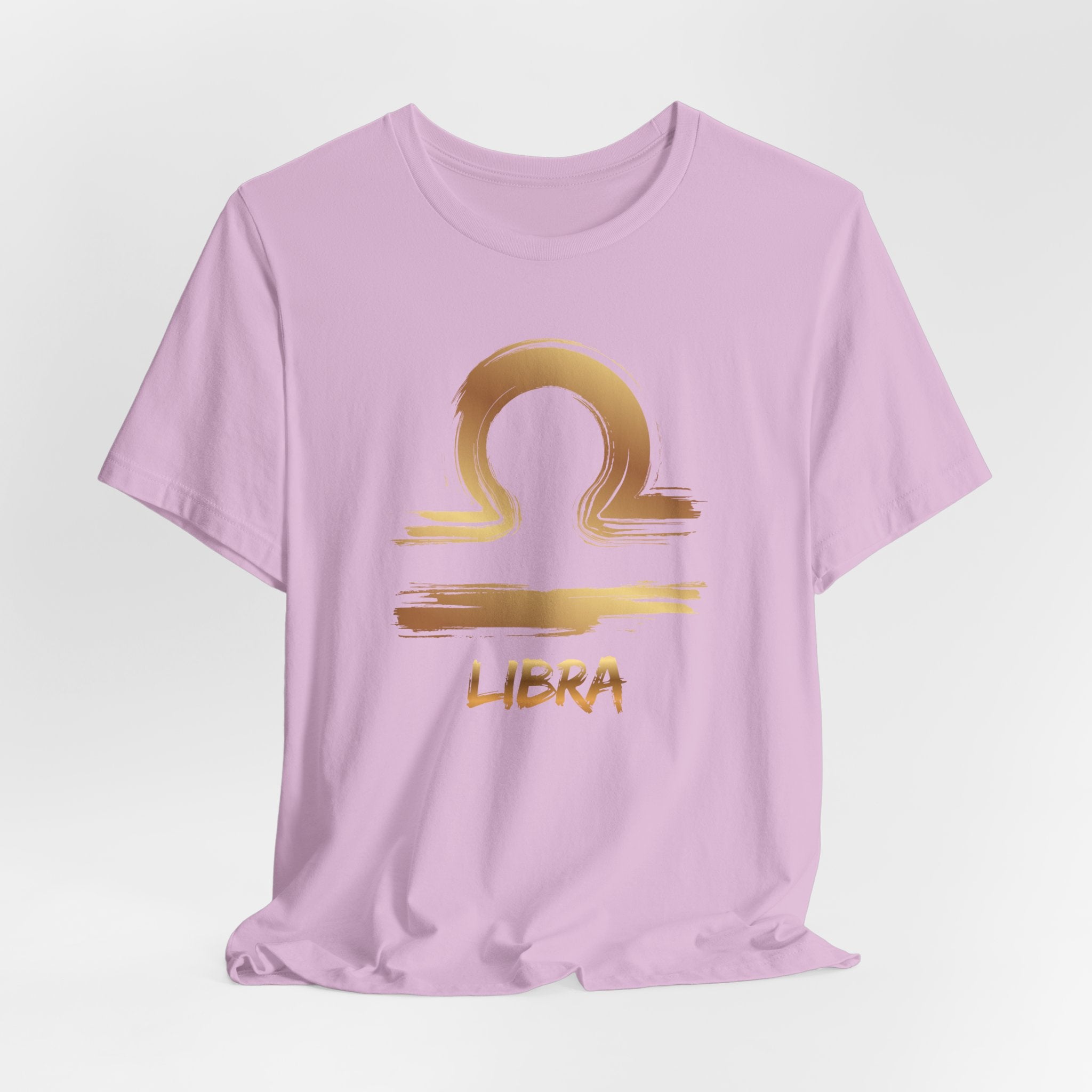 Pink t-shirt with gold Libra zodiac sign design on a light gray background