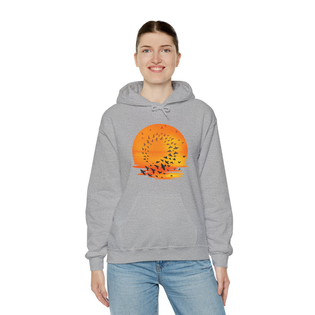 Person wearing a gray hoodie with a sunset and bird design on a white background