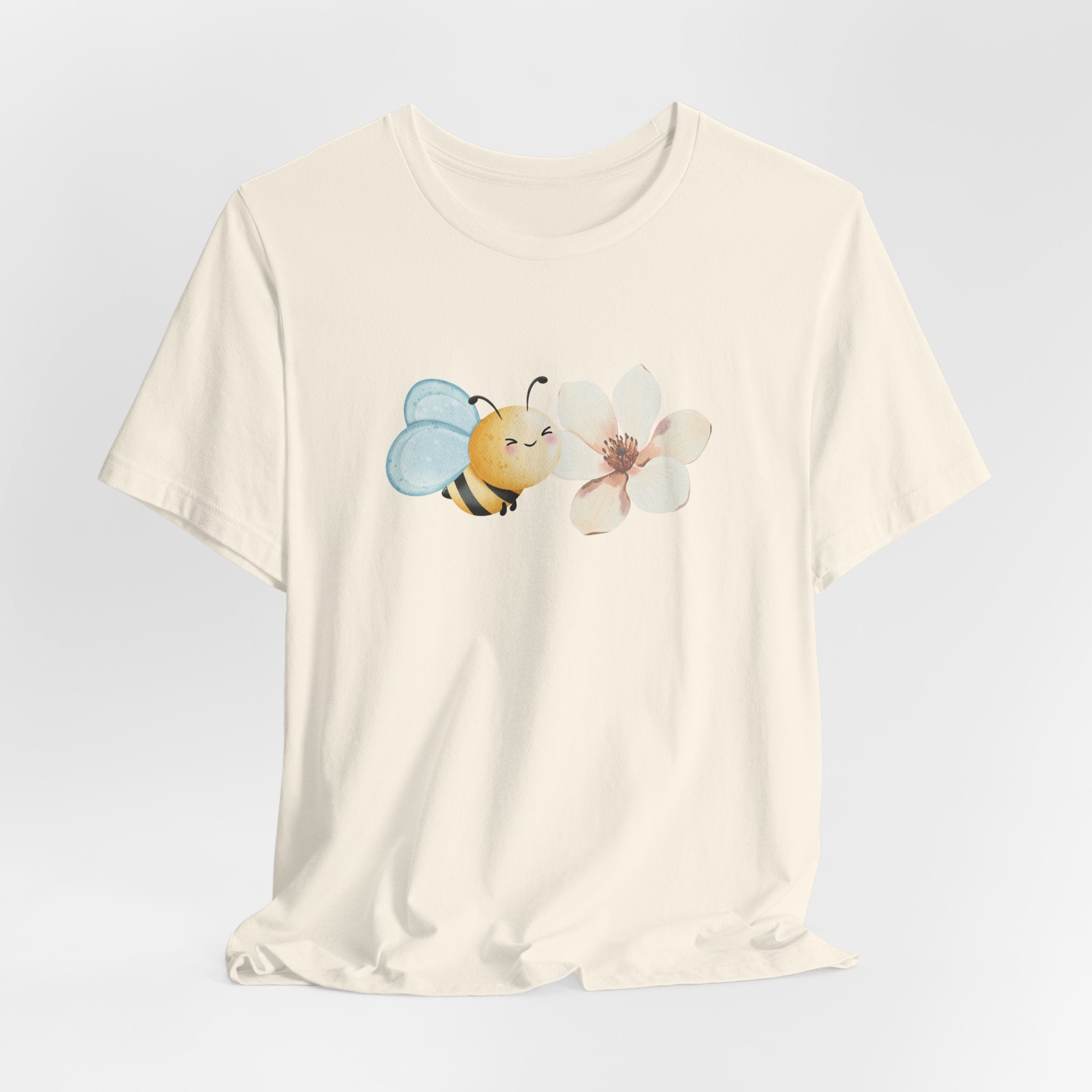 Beige t-shirt with a bee and flower graphic on a light gray background