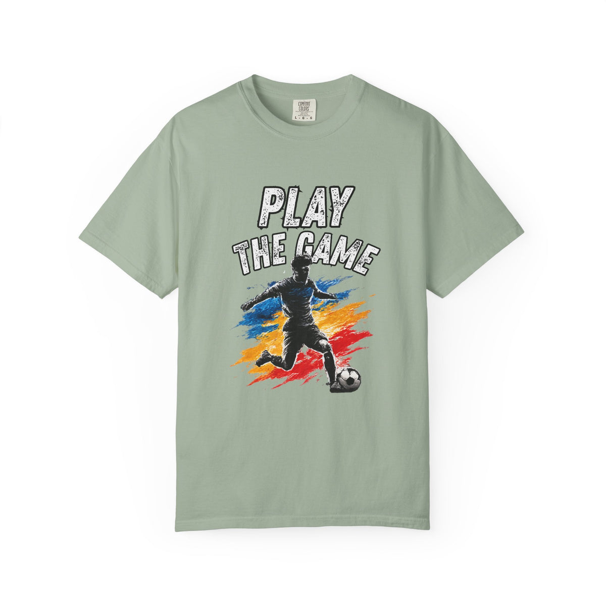 A sage green short-sleeve t-shirt with a graphic on the front showing a soccer player kicking a ball with the text 'PLAY THE GAME' above, set against a plain white background.