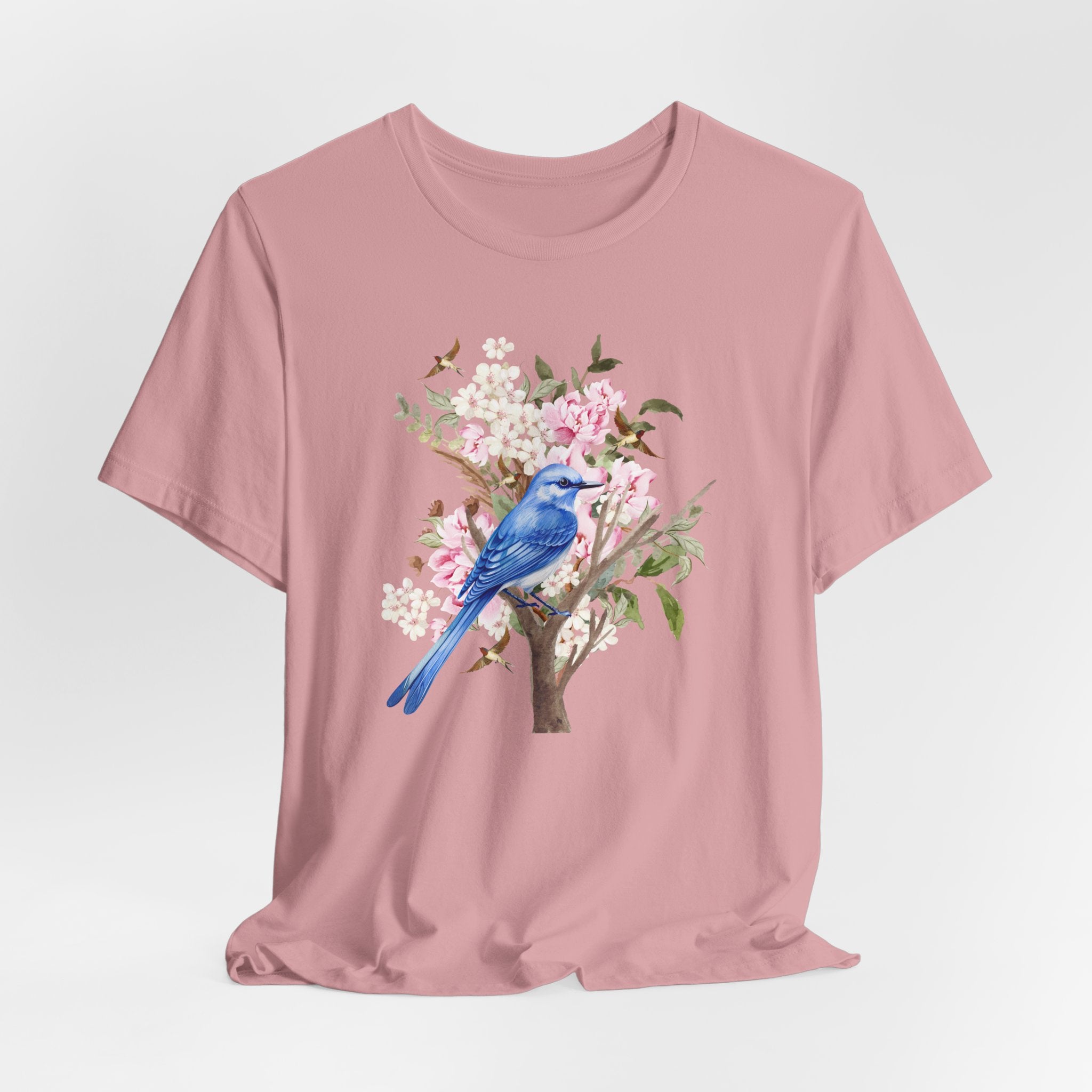 Pink t-shirt with a blue bird and floral design on a light gray background