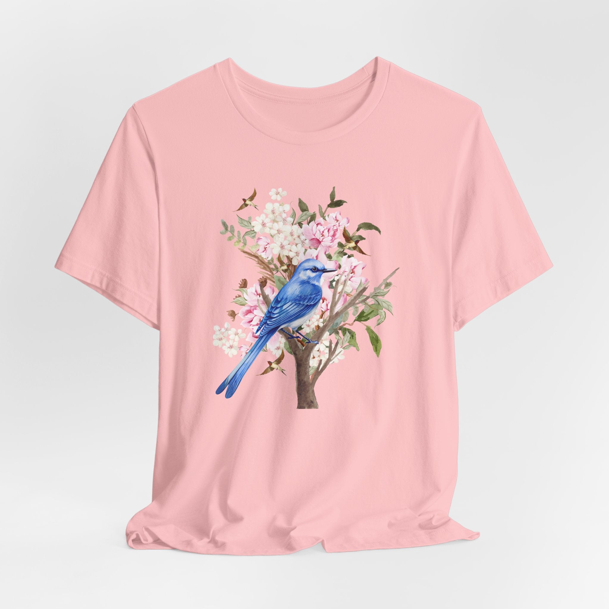 Pink t-shirt with a blue bird and floral design on a light gray background