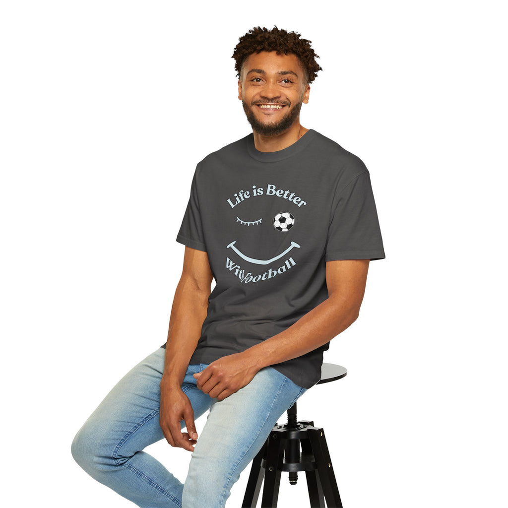 Man sitting on a stool wearing a dark gray t-shirt with 'Life is Better With Football' text and smiley face design on a white background