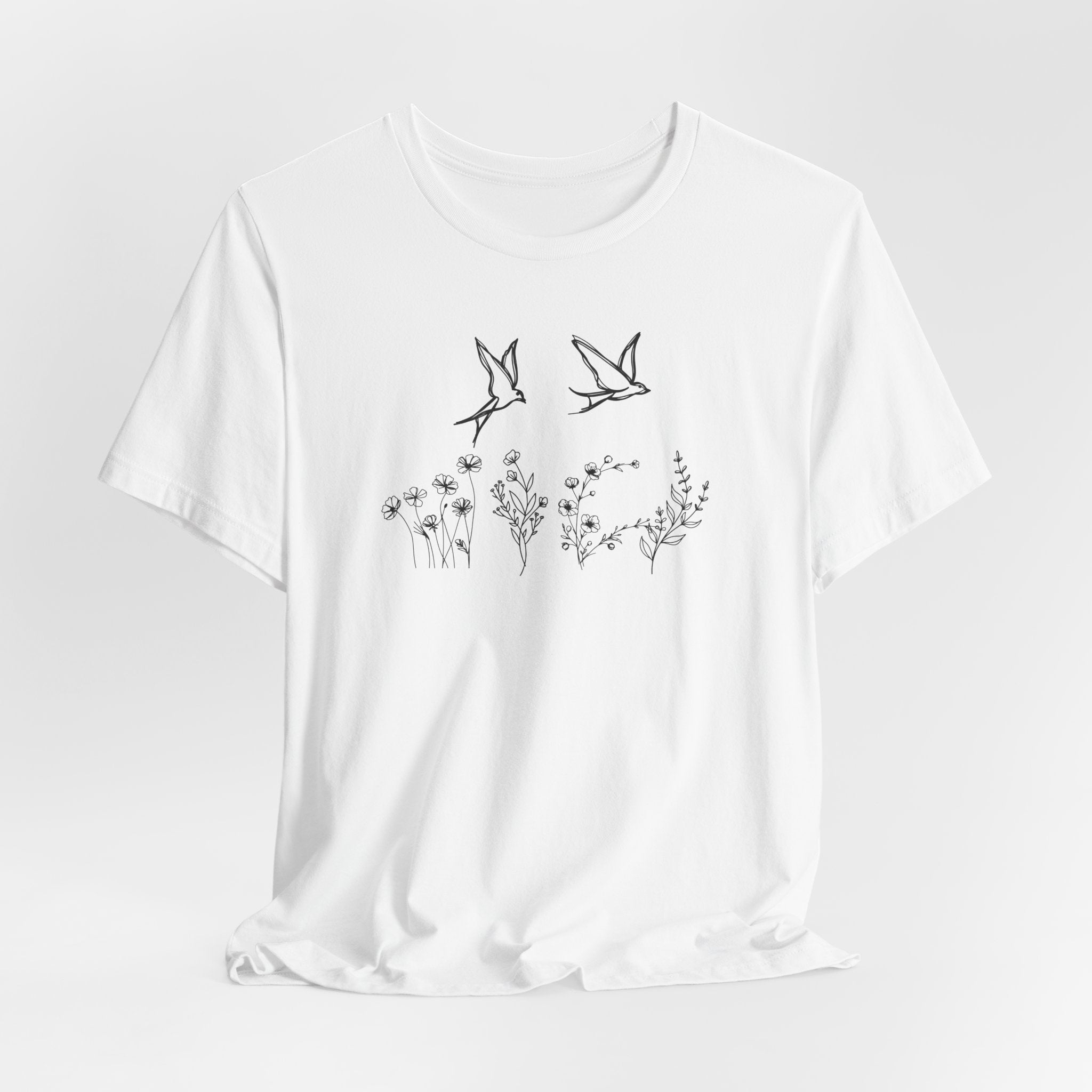 White t-shirt with black bird and floral design on a white background