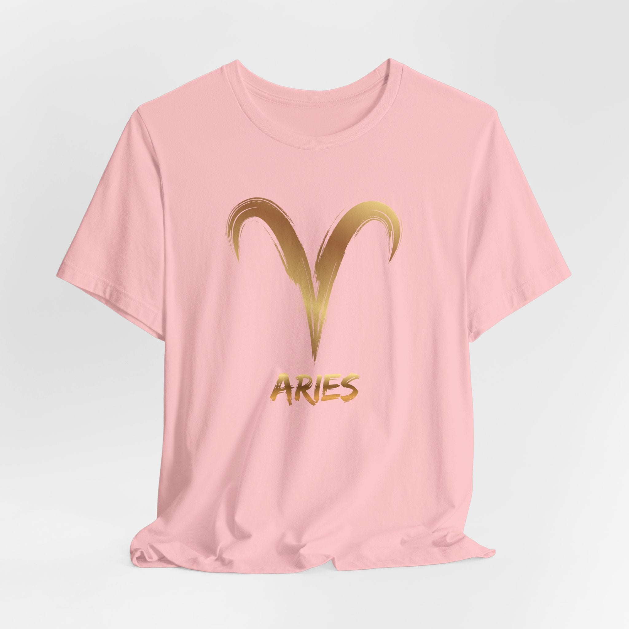 Pink t-shirt with gold Aries symbol and text on a light gray background