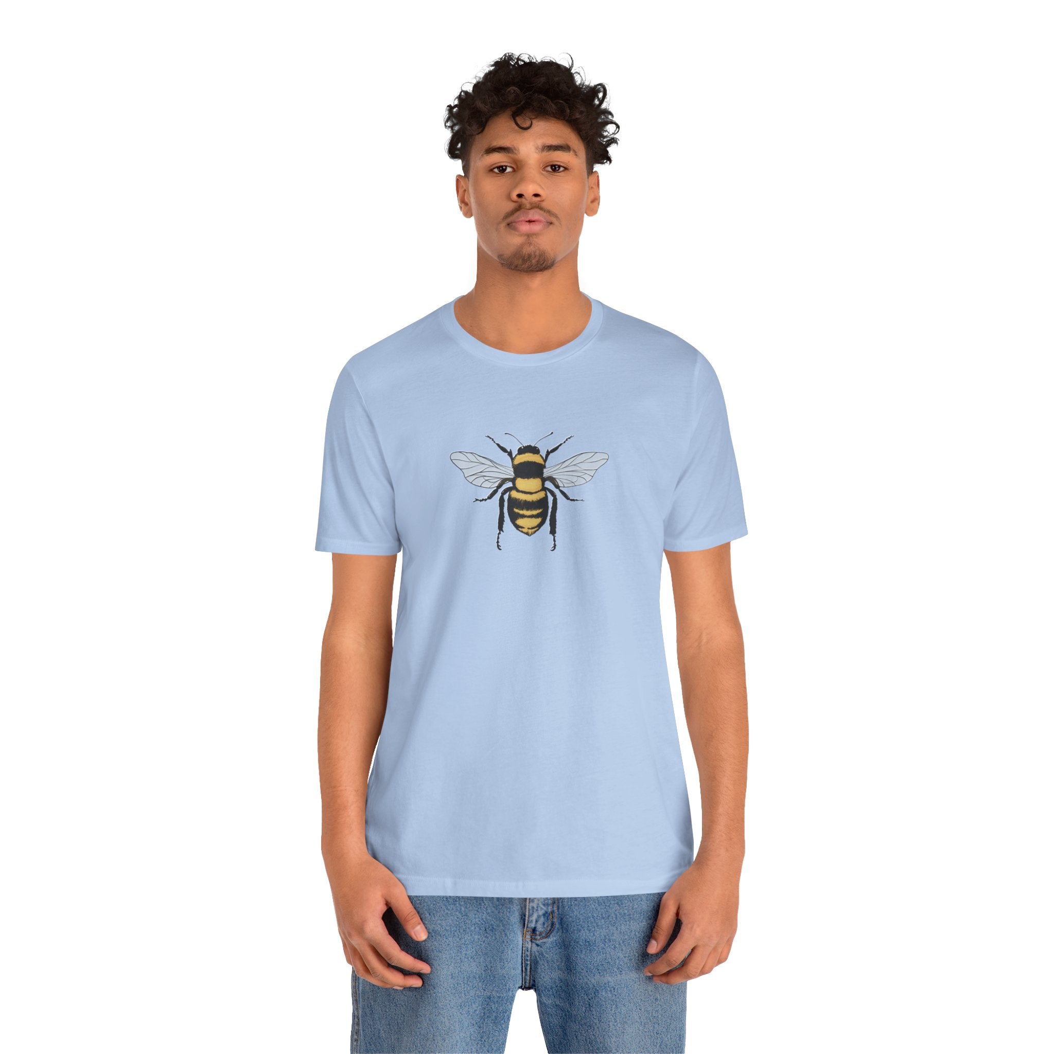 Person wearing a light blue t-shirt with a bee design on a white background