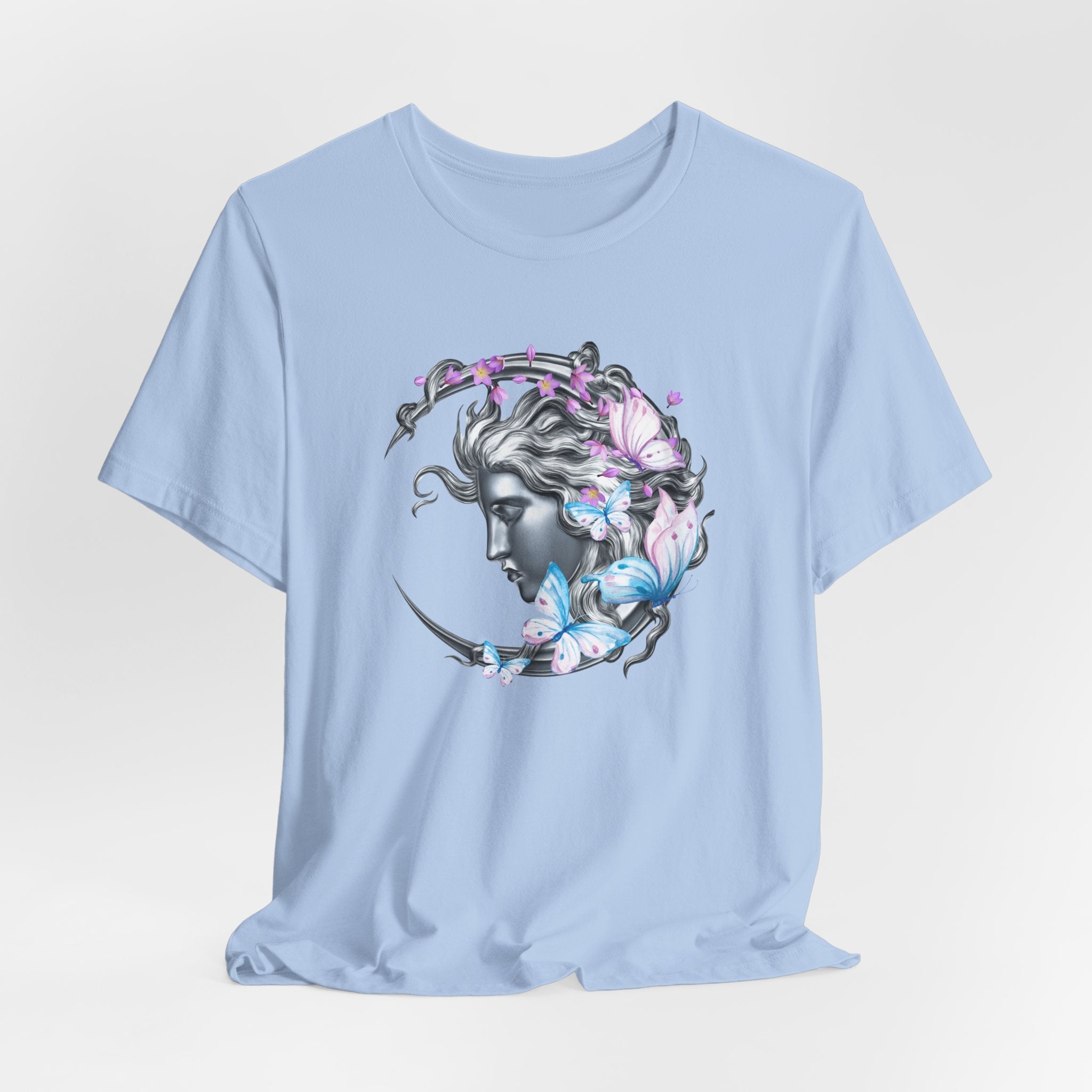 Light blue t-shirt with a decorative design of a face with flowers and butterflies on a light gray background