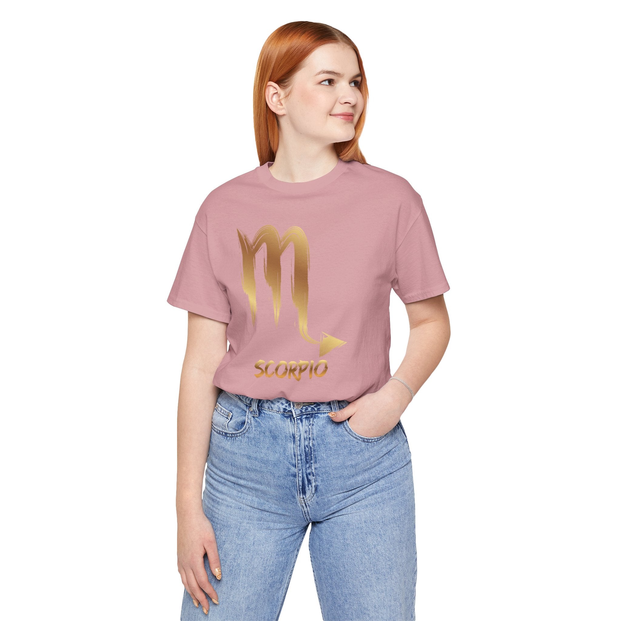 Person wearing a pink t-shirt with a gold Scorpio symbol design on a white background