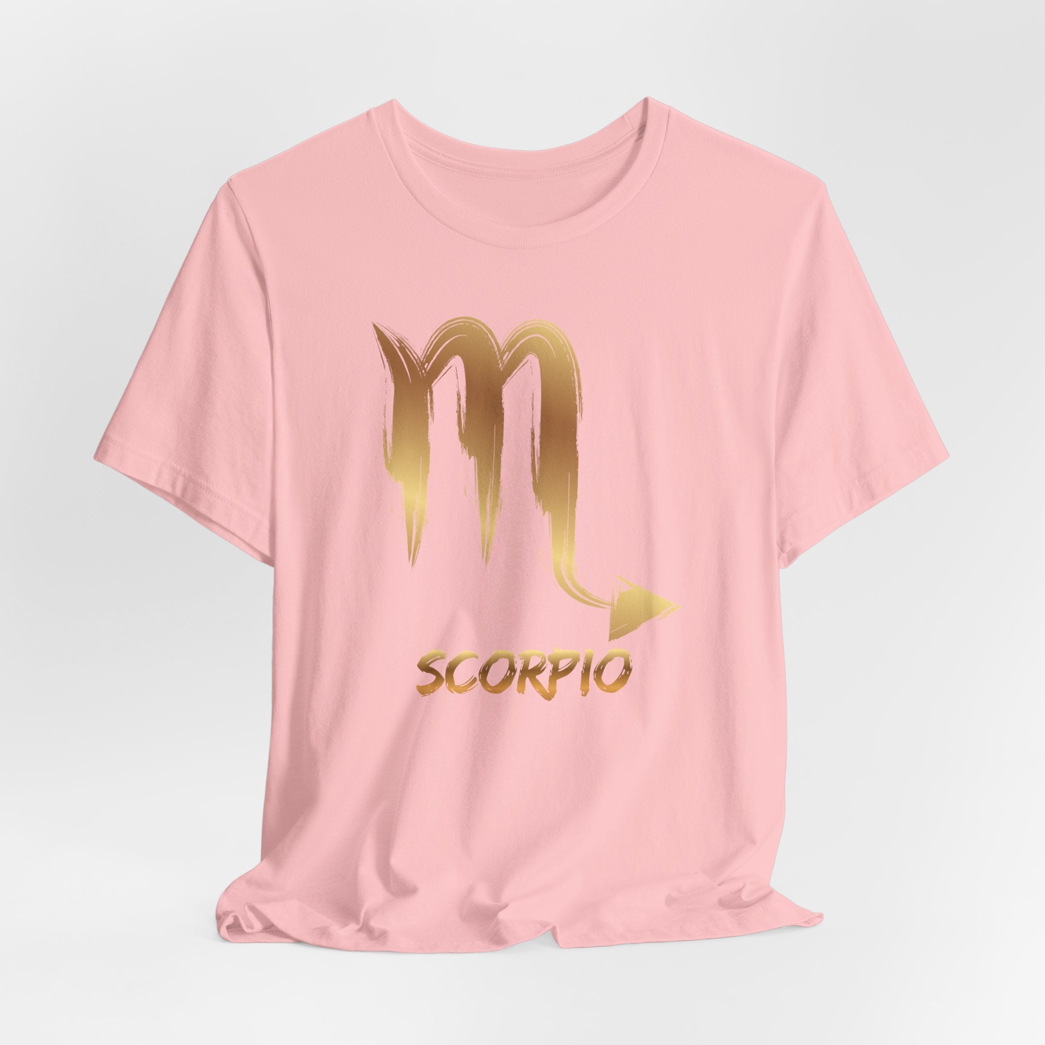 Pink t-shirt with gold Scorpio symbol and text on a light gray background