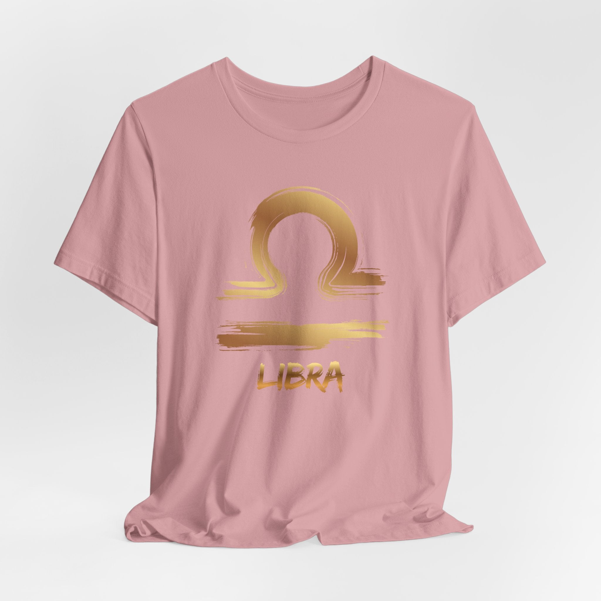 Pink t-shirt with gold Libra zodiac symbol on a light gray background