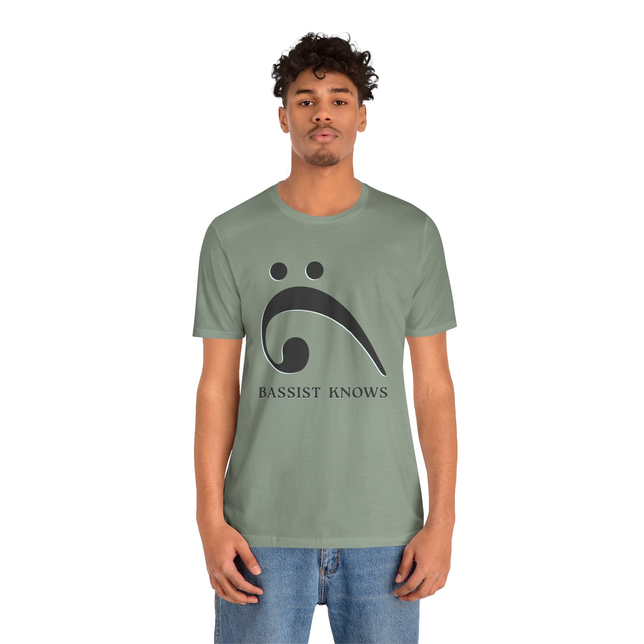 Person wearing a green t-shirt with black bass clef and 'Bassist Knows' text on a light gray background