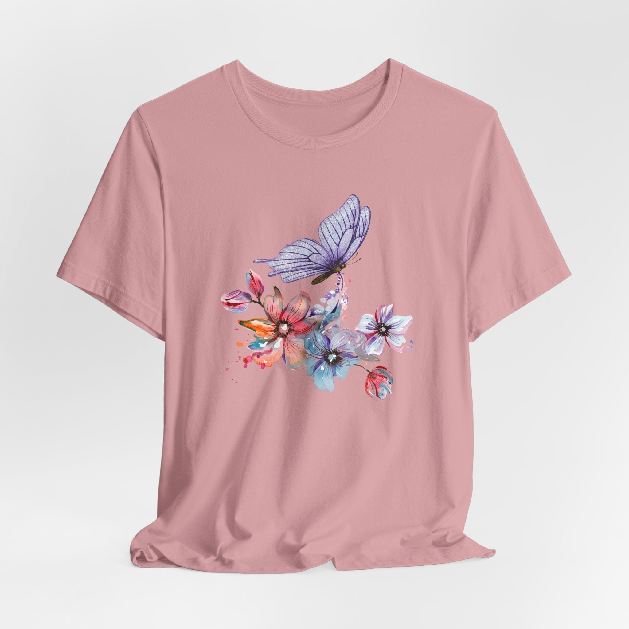 Pink t-shirt with a colorful butterfly and floral design on a light gray background