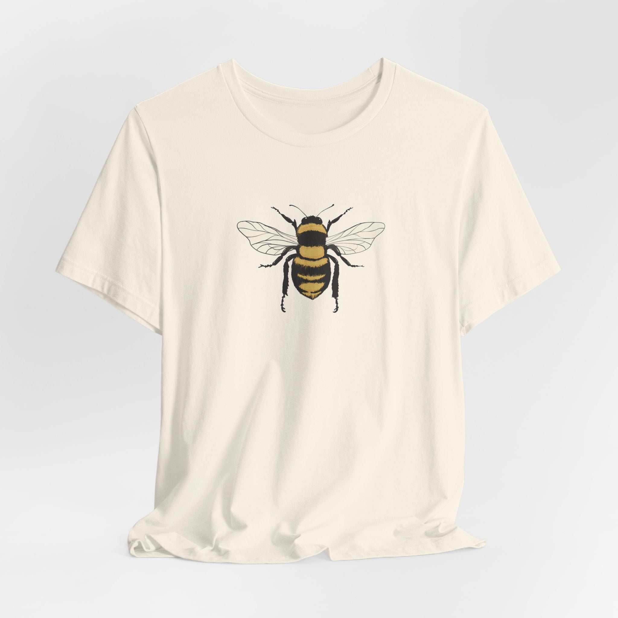 White t-shirt with a bee design on a light gray background