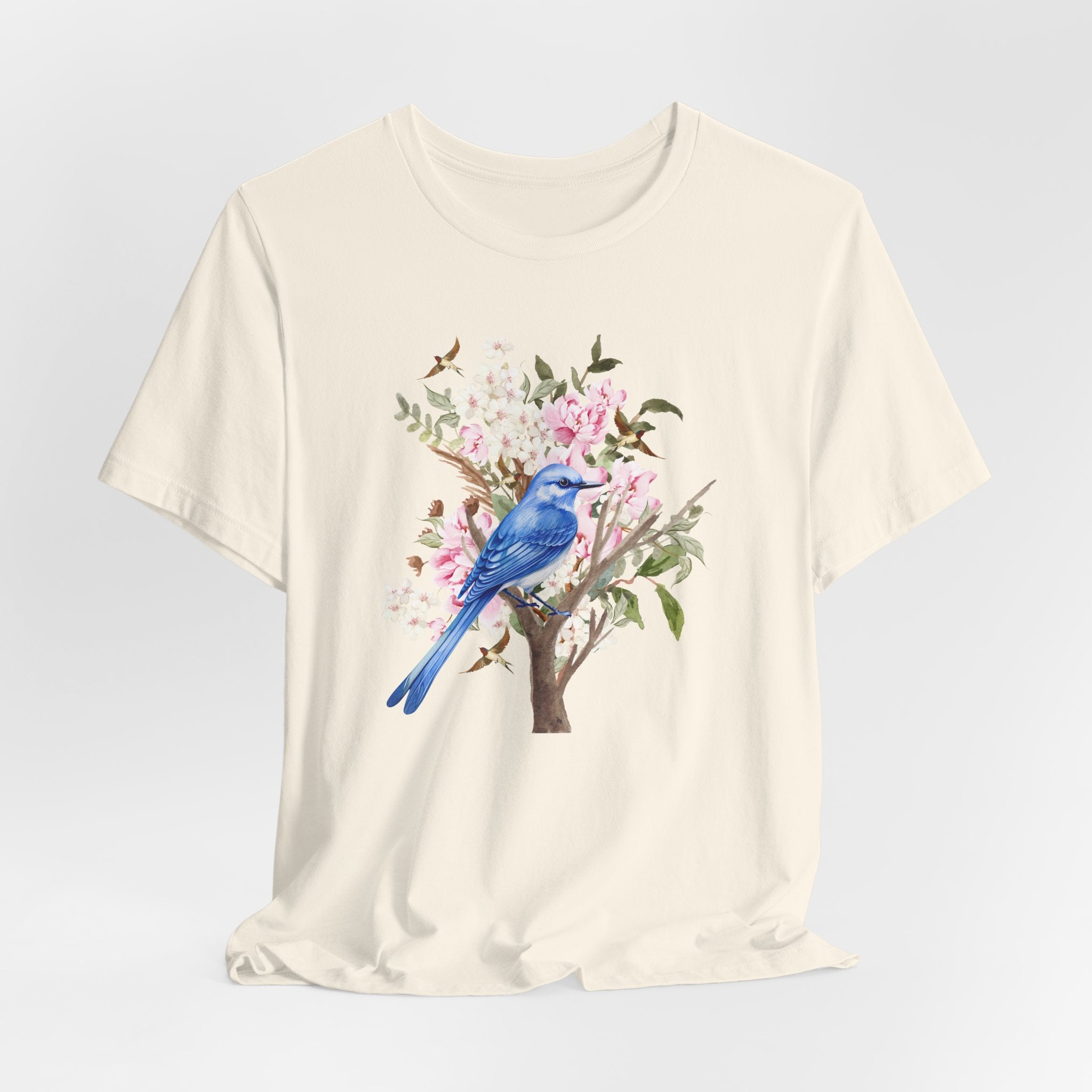 Beige t-shirt with a blue bird and floral design on a light gray background