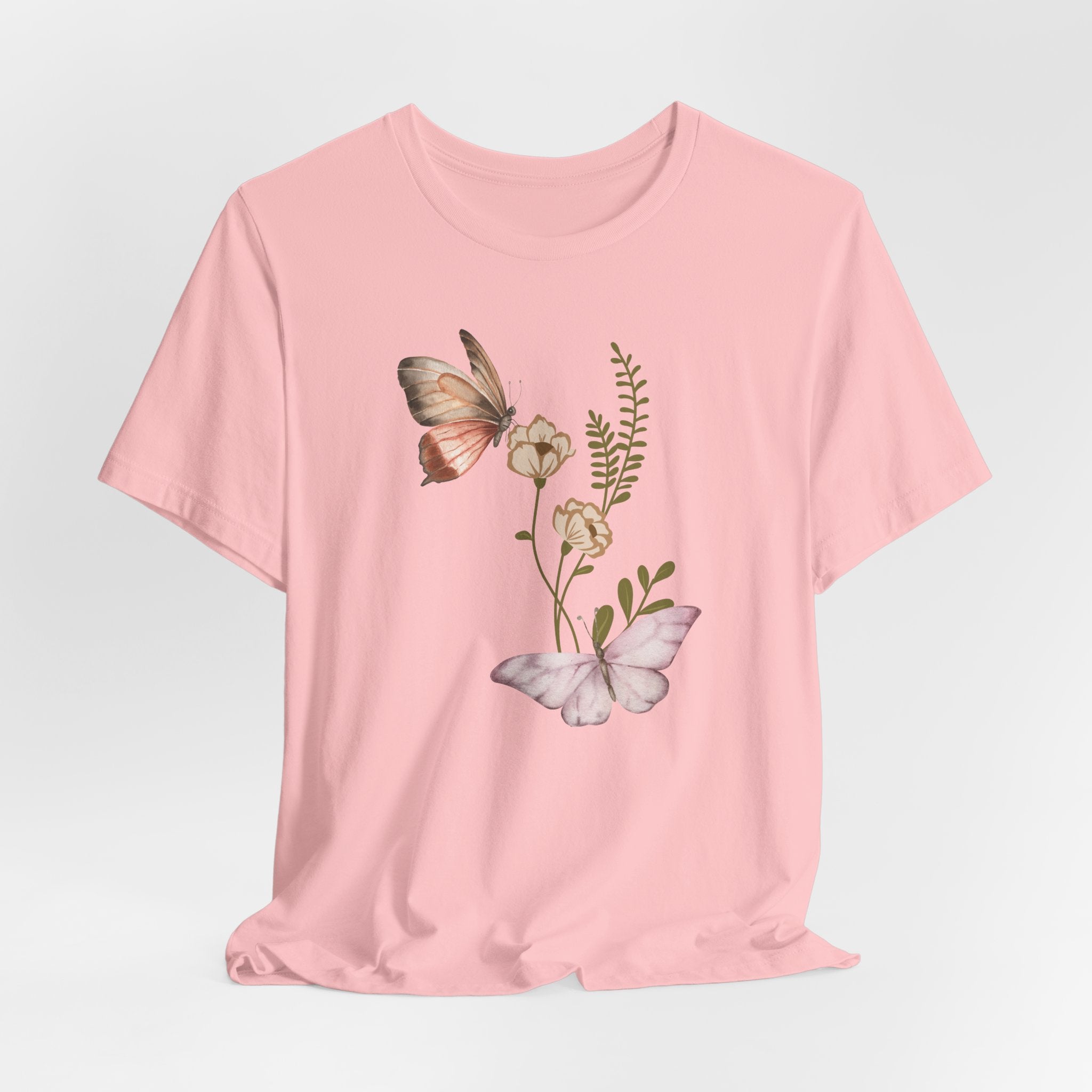 Pink t-shirt with butterfly and floral design on a light gray background