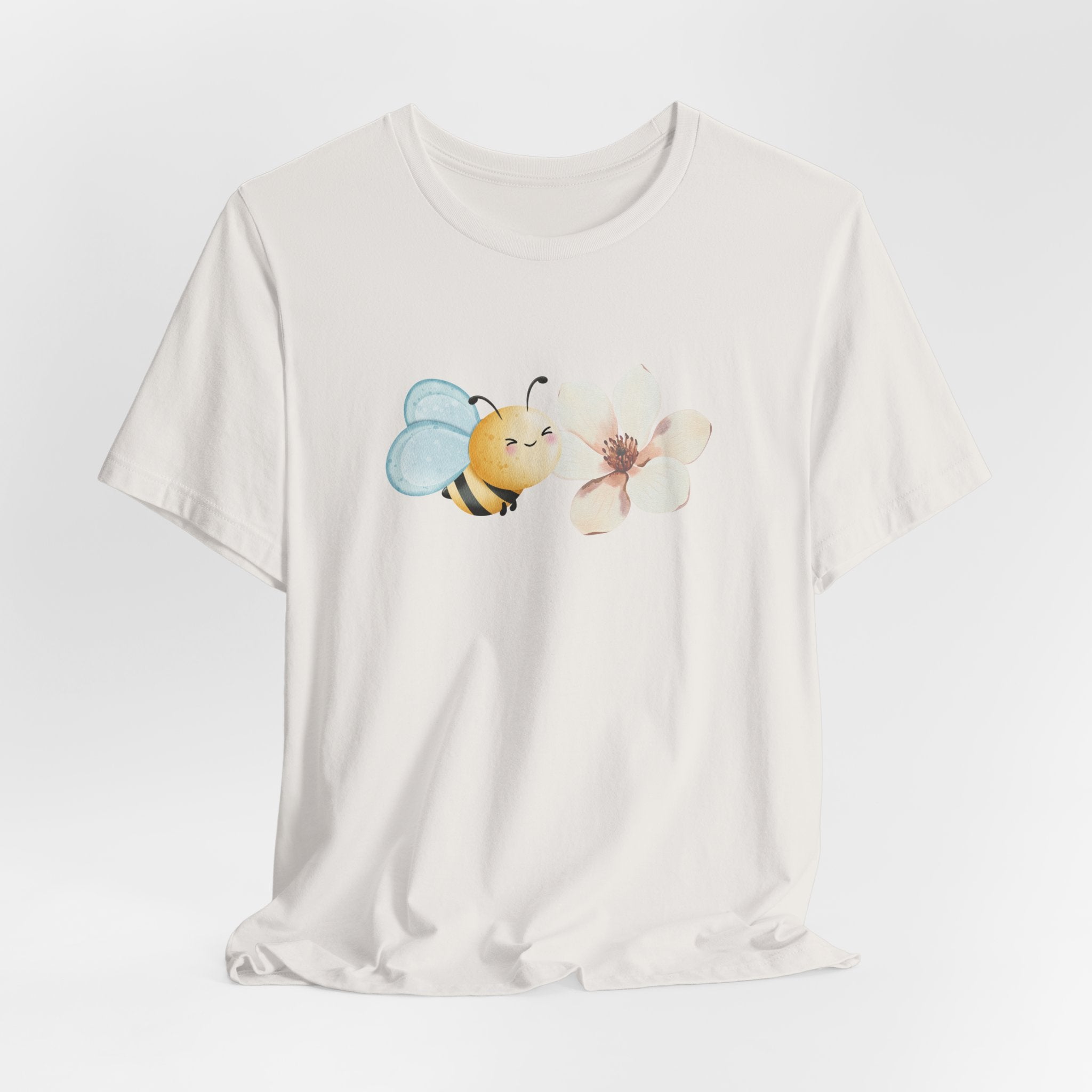 White t-shirt with a bee and flower graphic on a light gray background