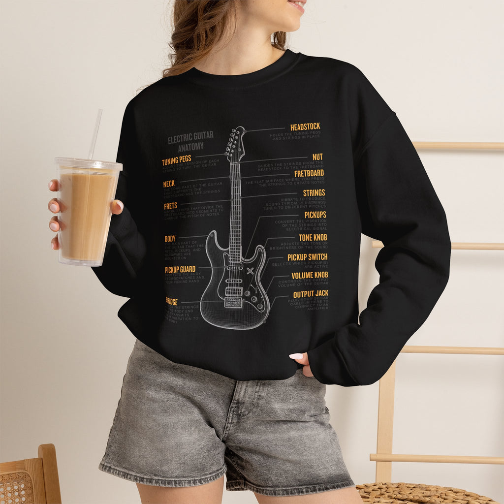 Person wearing a black sweatshirt with a electric guitar anatomy diagram design, holding a drink.