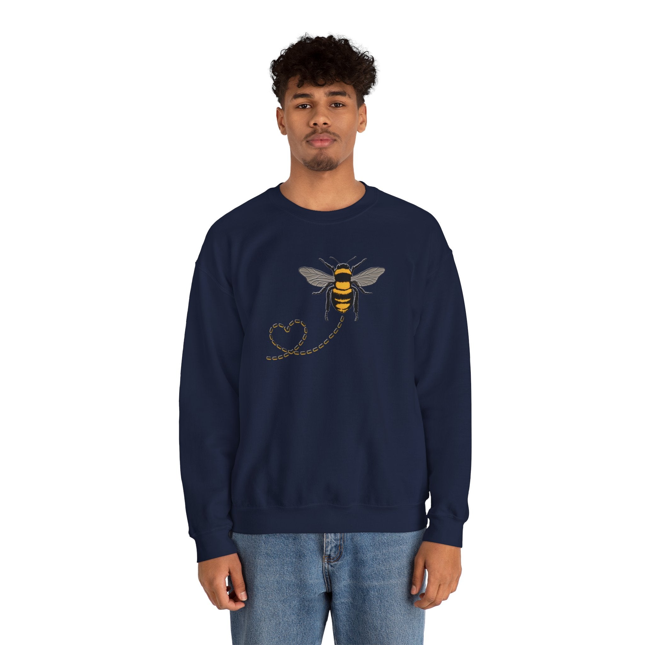 Person wearing a navy blue sweatshirt with a bee and dotted heart design on a white background
