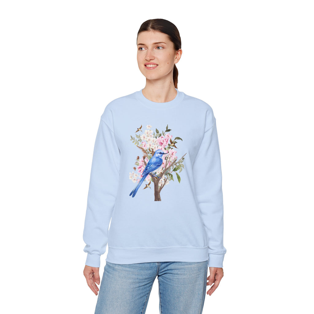 Woman wearing a light blue sweatshirt with a floral and bird design on a white background