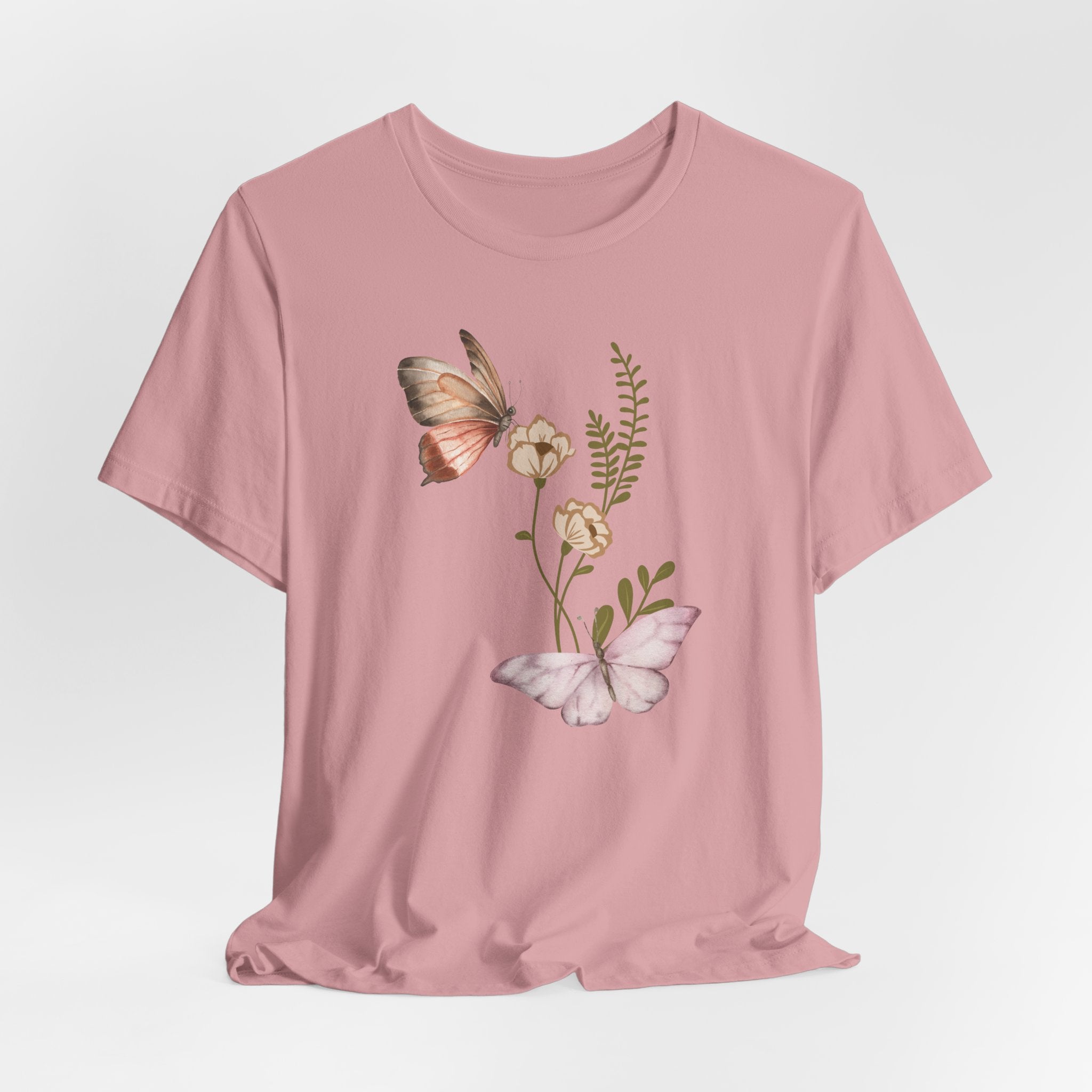 Pink t-shirt with butterfly and floral design on a light gray background