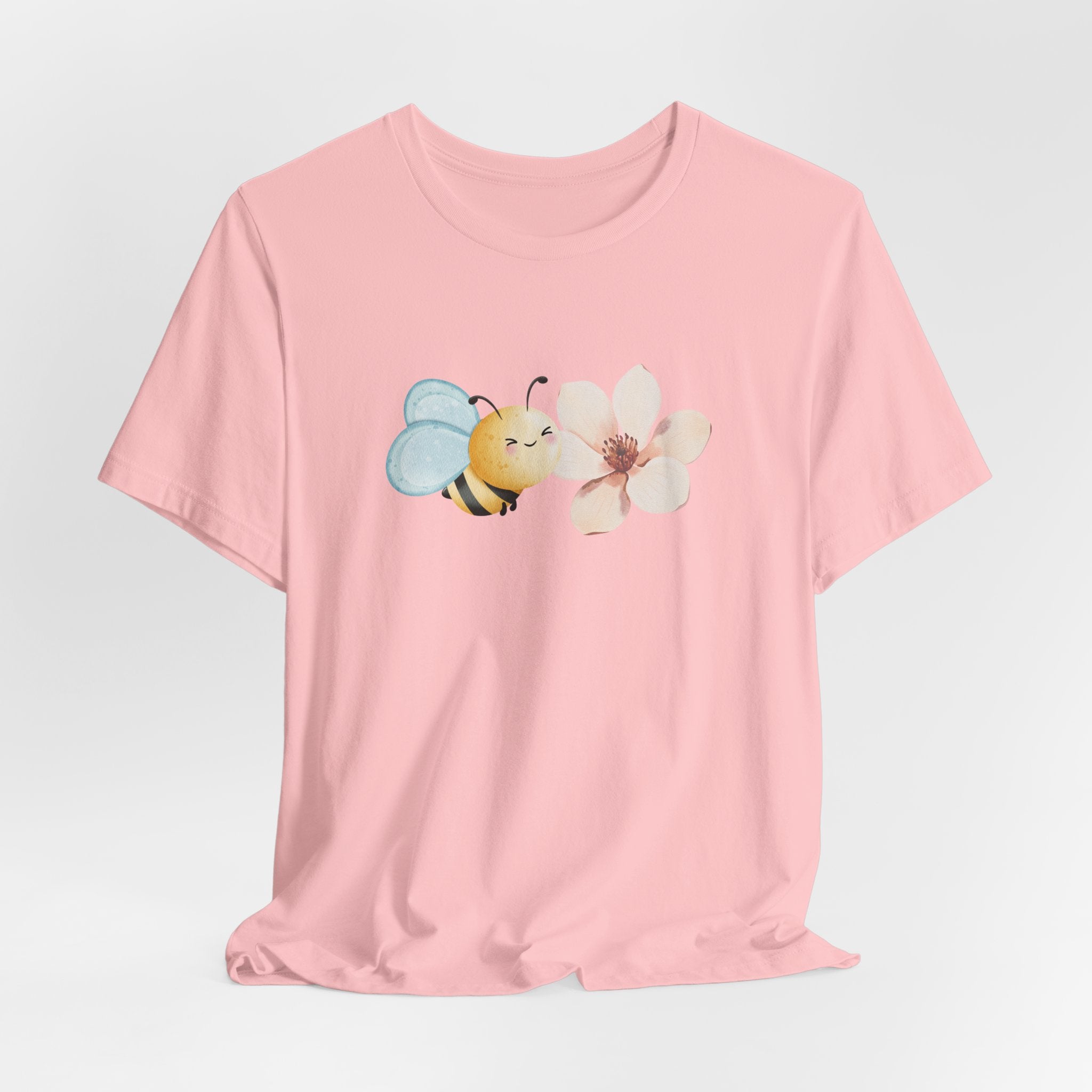 Pink t-shirt with a bee and flower graphic on a light gray background