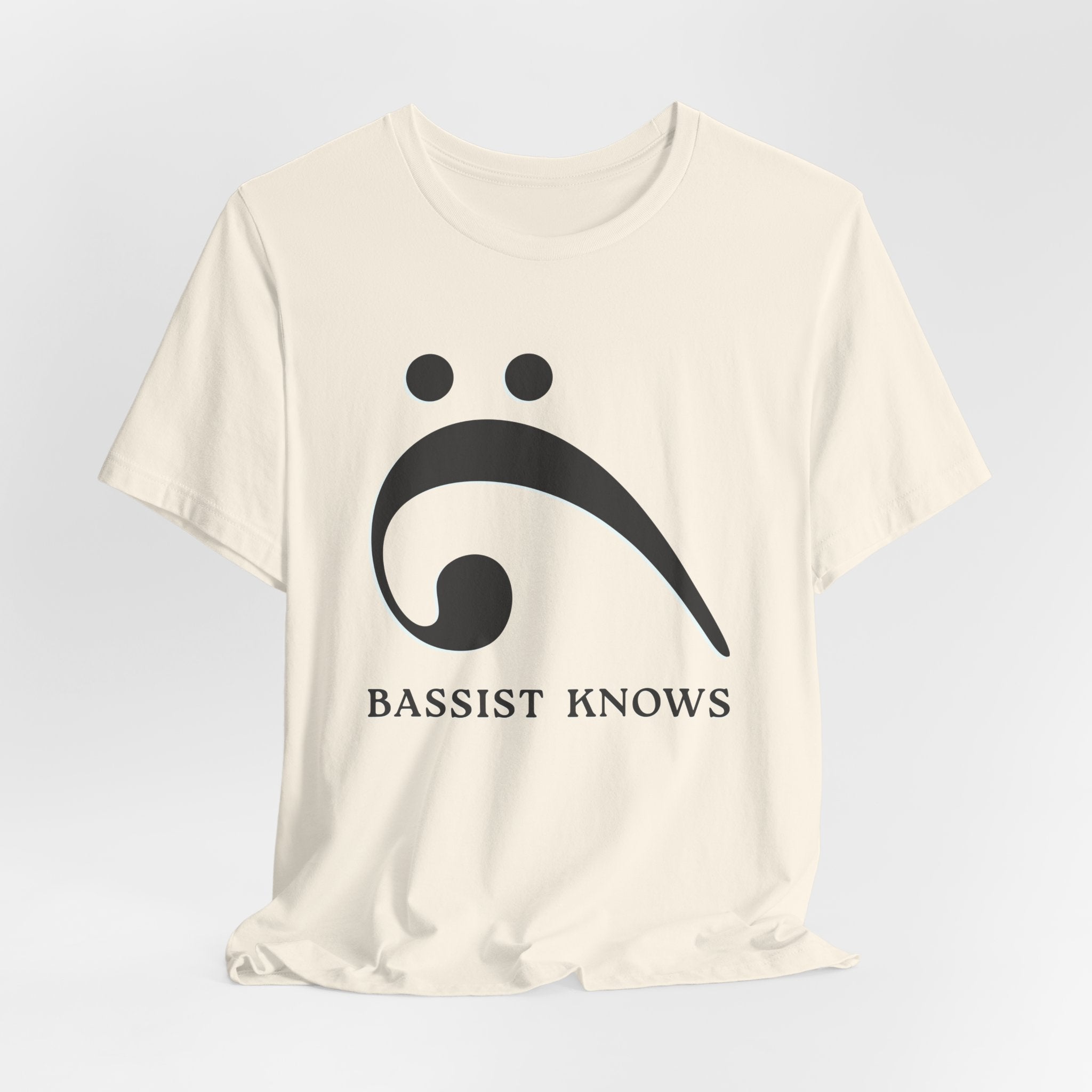 Beige t-shirt with black bass clef and 'Bassist Knows' text on a light gray background