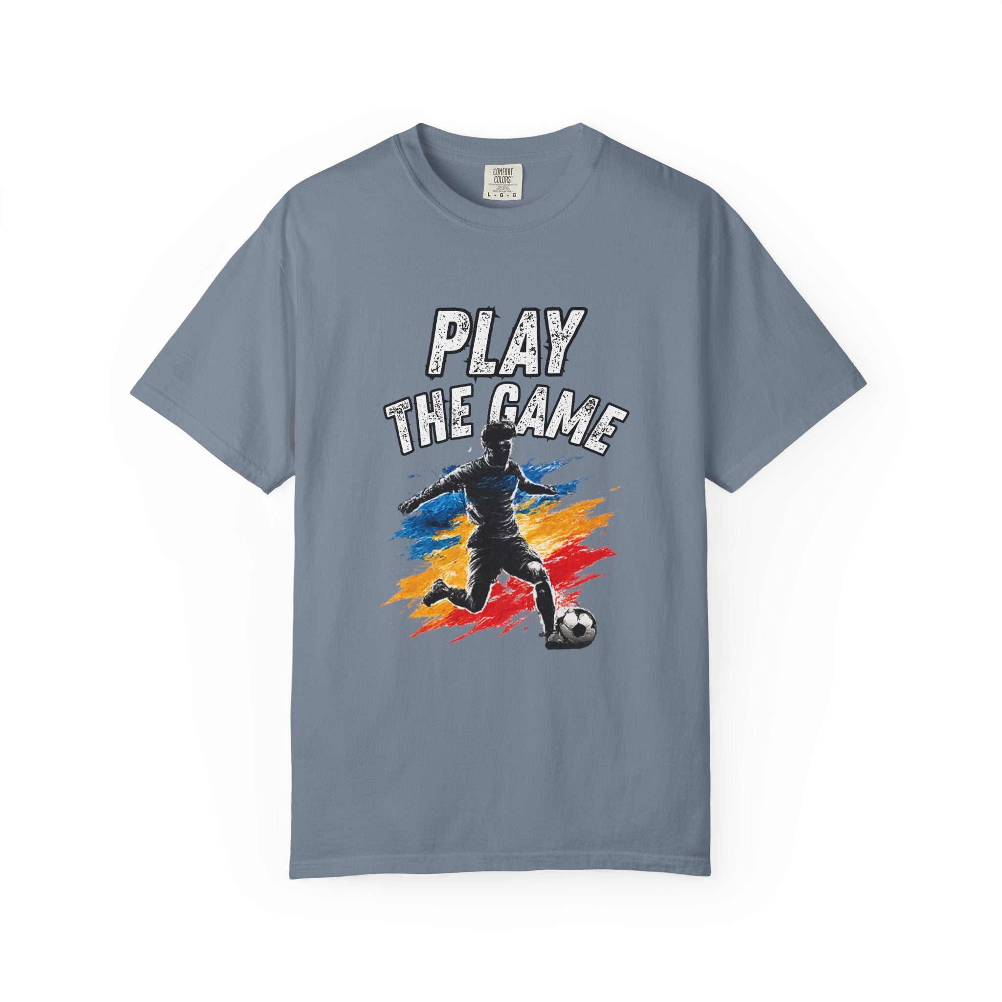 A slate blue short-sleeve t-shirt with a graphic on the front showing a soccer player kicking a ball with the text 'PLAY THE GAME' above, set against a plain white background.