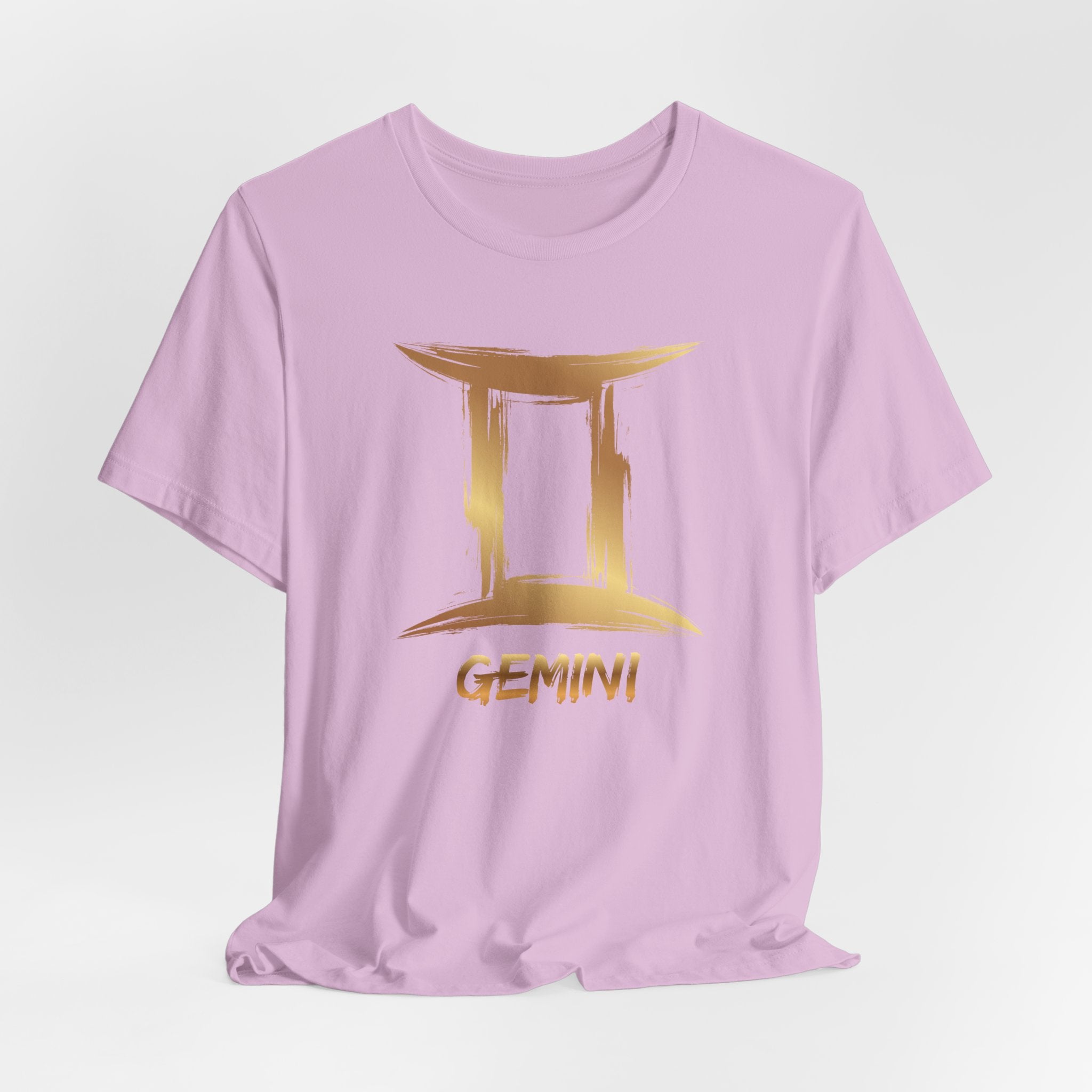 Pink t-shirt with gold Gemini zodiac sign design on a light gray background