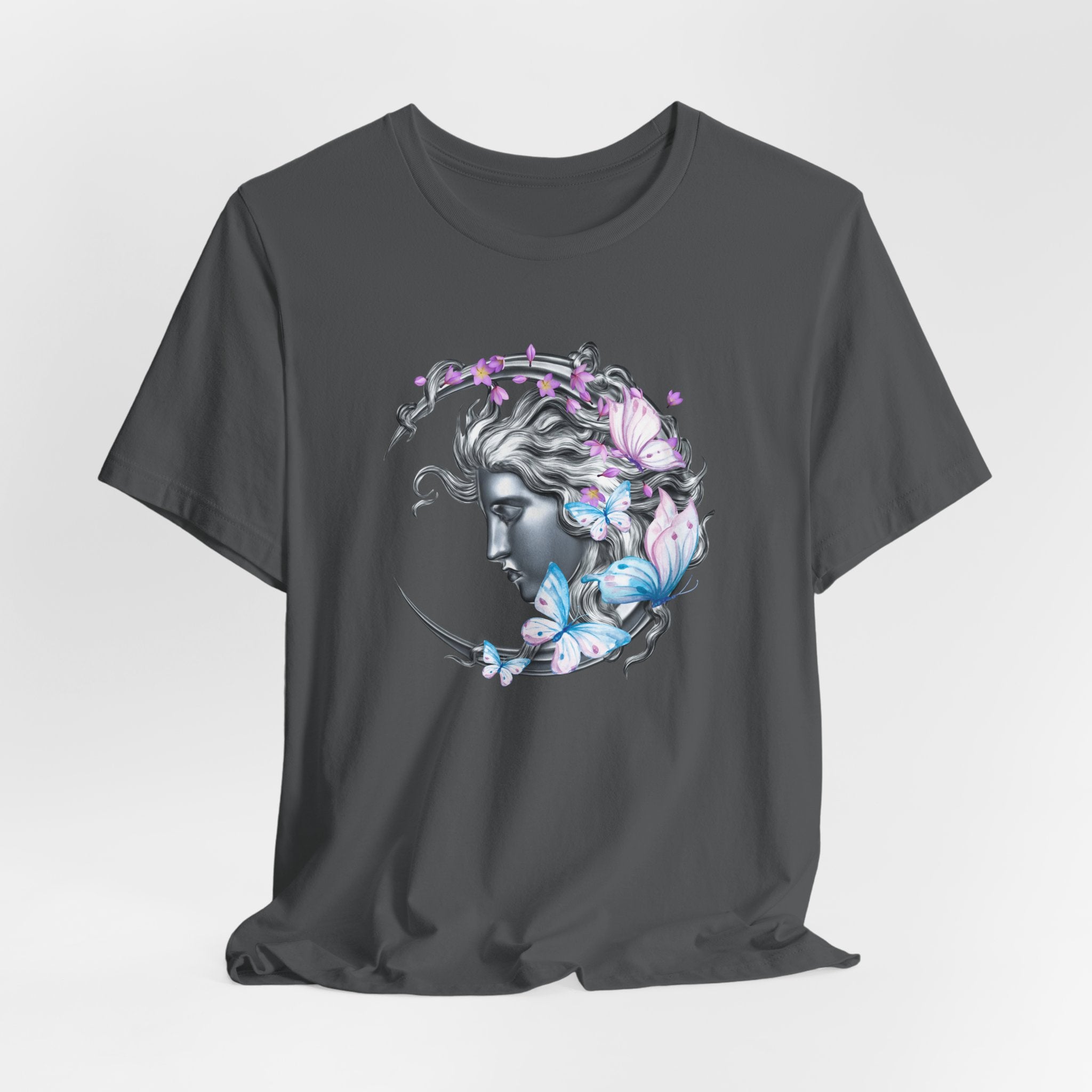 Gray t-shirt with a decorative design of a face surrounded by flowers and butterflies on a light gray background.