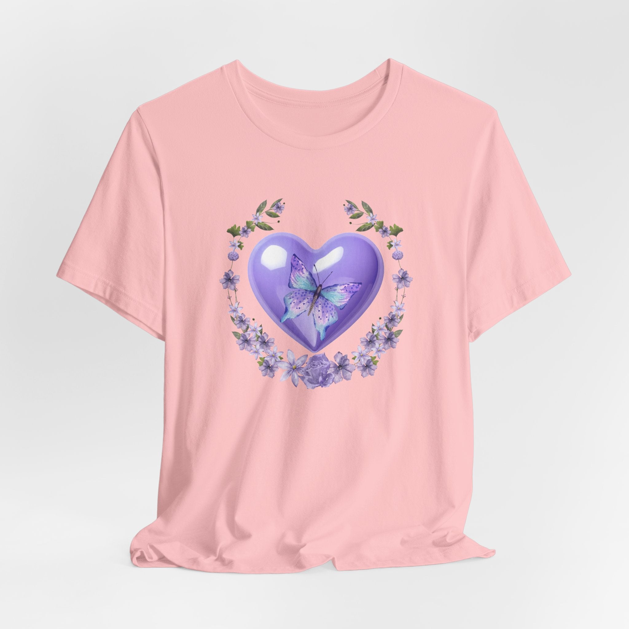 Pink t-shirt with a purple heart and butterfly design on a light gray background