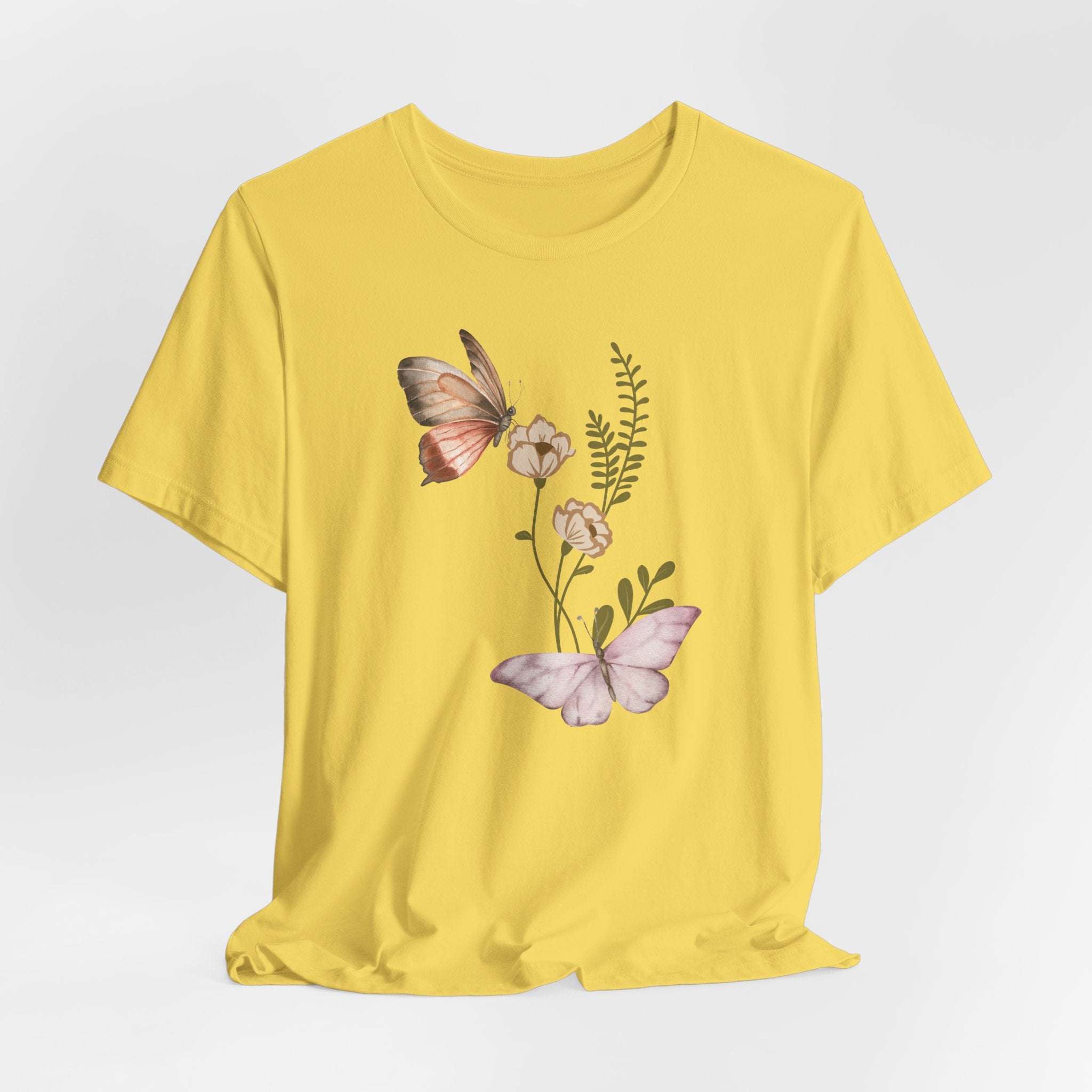 Yellow t-shirt with butterfly and floral design on a light gray background
