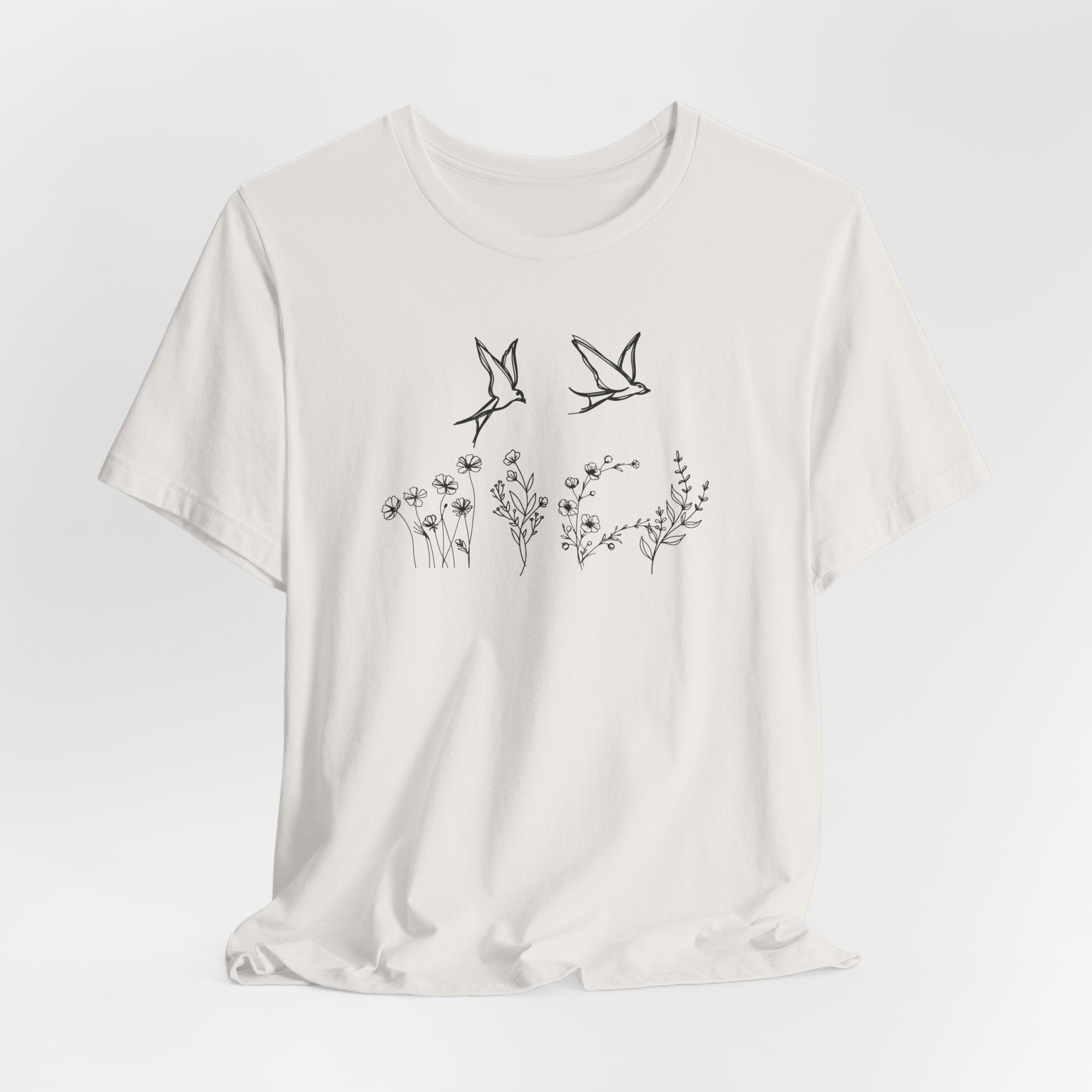 White t-shirt with black bird and floral design on a light gray background