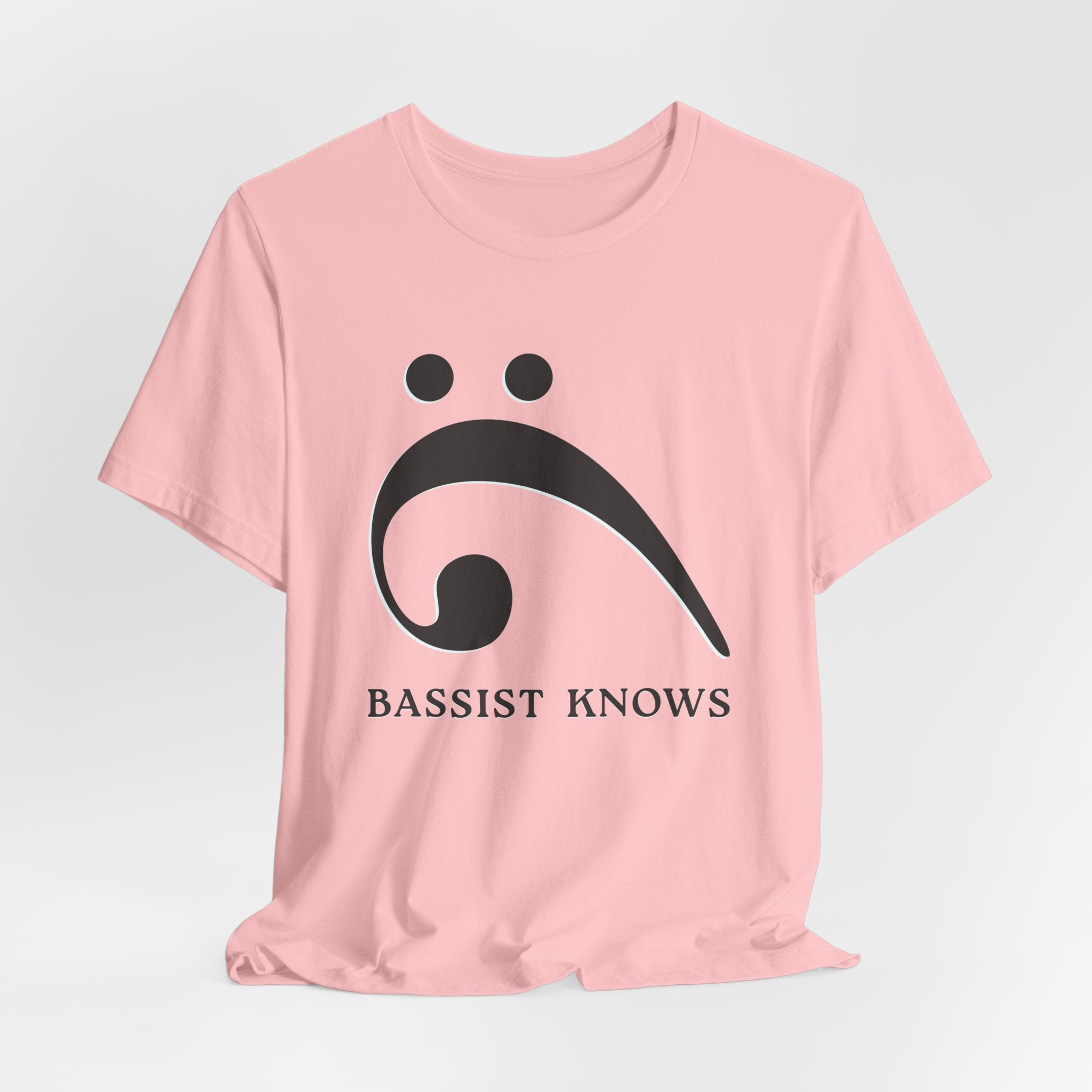 Pink t-shirt with black bass clef and 'Bassist Knows' text on a light gray background