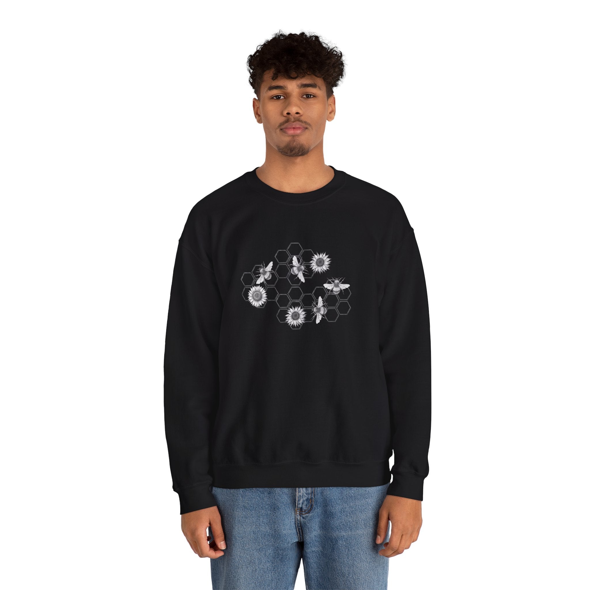 Person wearing a black sweatshirt with bee and flower pattern on a white background