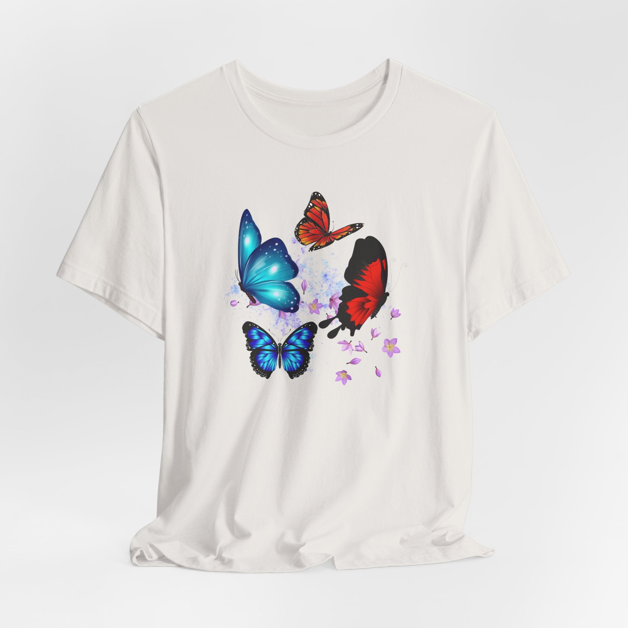 White t-shirt with colorful butterfly designs on a light gray background