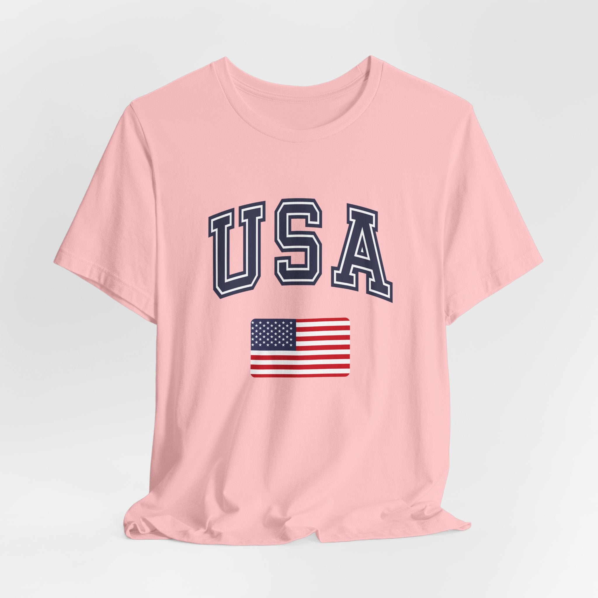 Pink t-shirt with 'USA' text and American flag on a light gray background