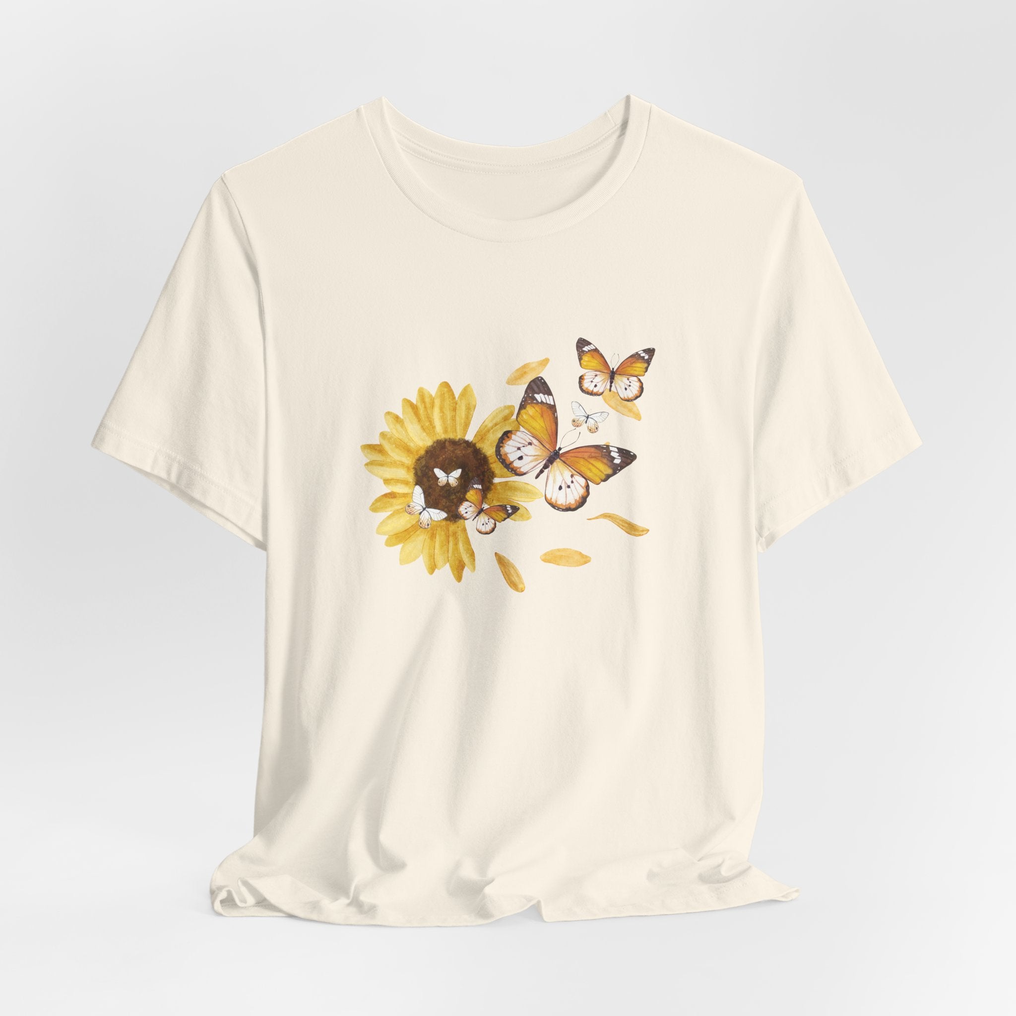 Beige t-shirt with a sunflower and butterfly graphic on a light gray background