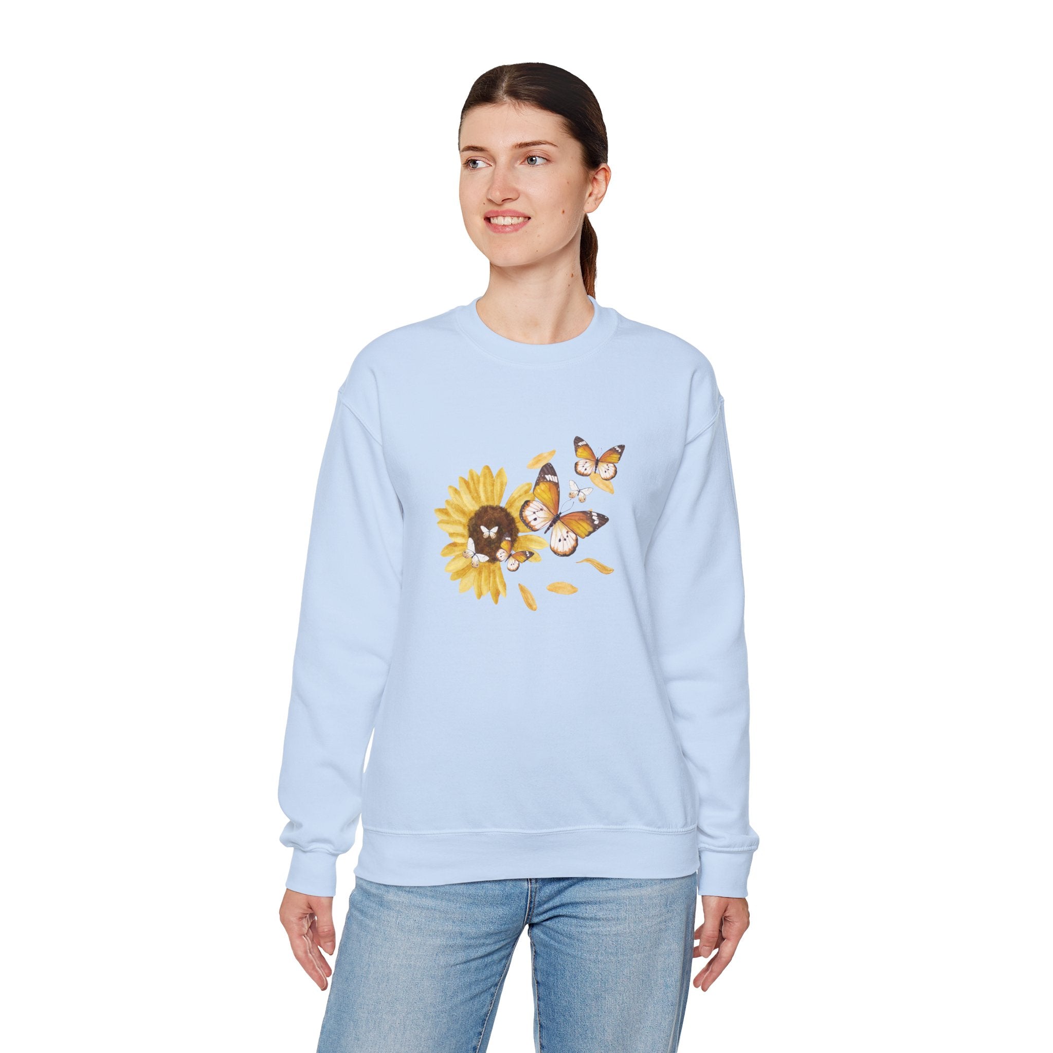 Woman wearing a light blue sweatshirt with a sunflower and butterfly design on a white background
