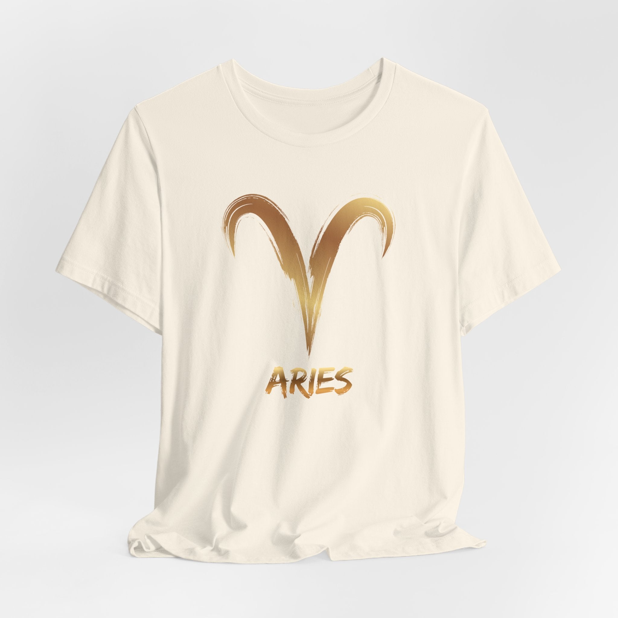 White t-shirt with gold Aries symbol and text on a light gray background