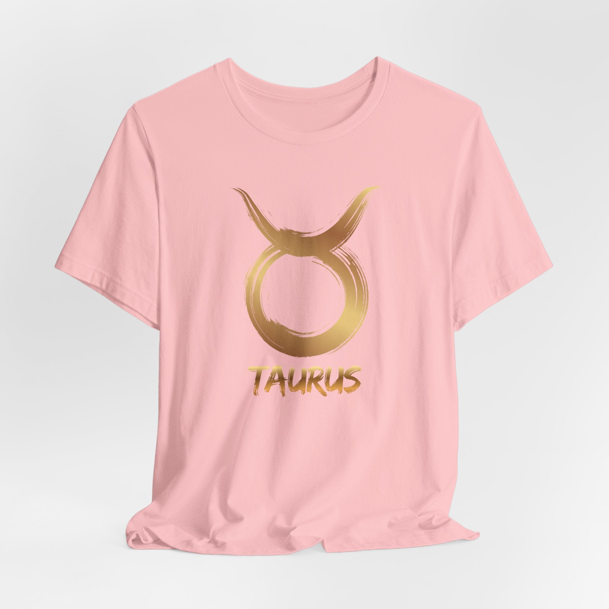 Pink t-shirt with gold Taurus symbol on a light gray background