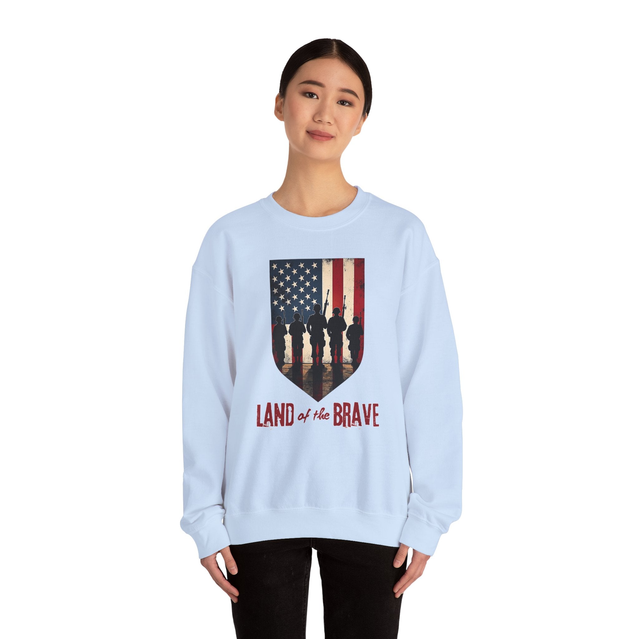 Light blue sweatshirt with American flag design and 'Land of the Brave' text worn by a person on a white background
