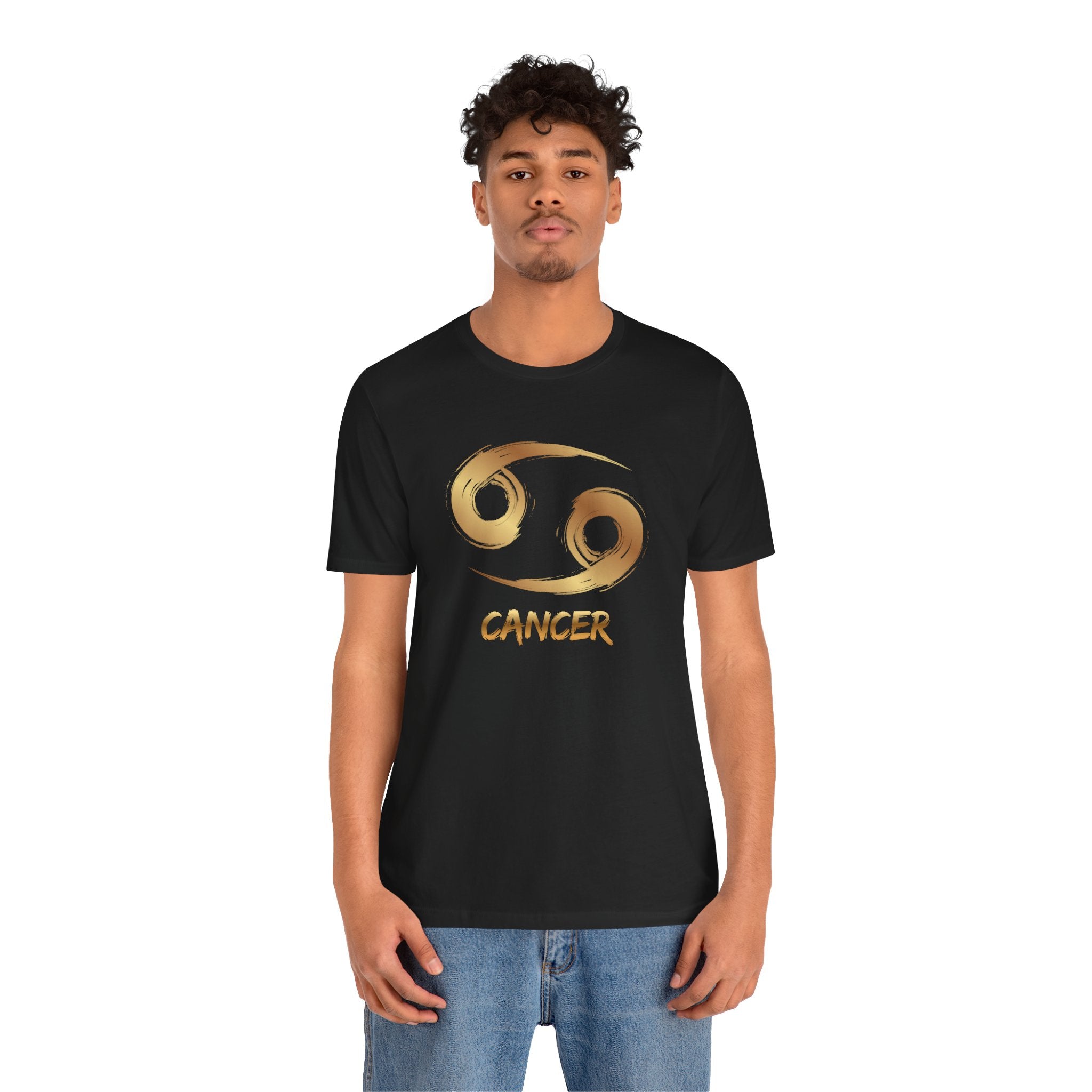 Person wearing a black t-shirt with a gold Cancer zodiac symbol on a white background