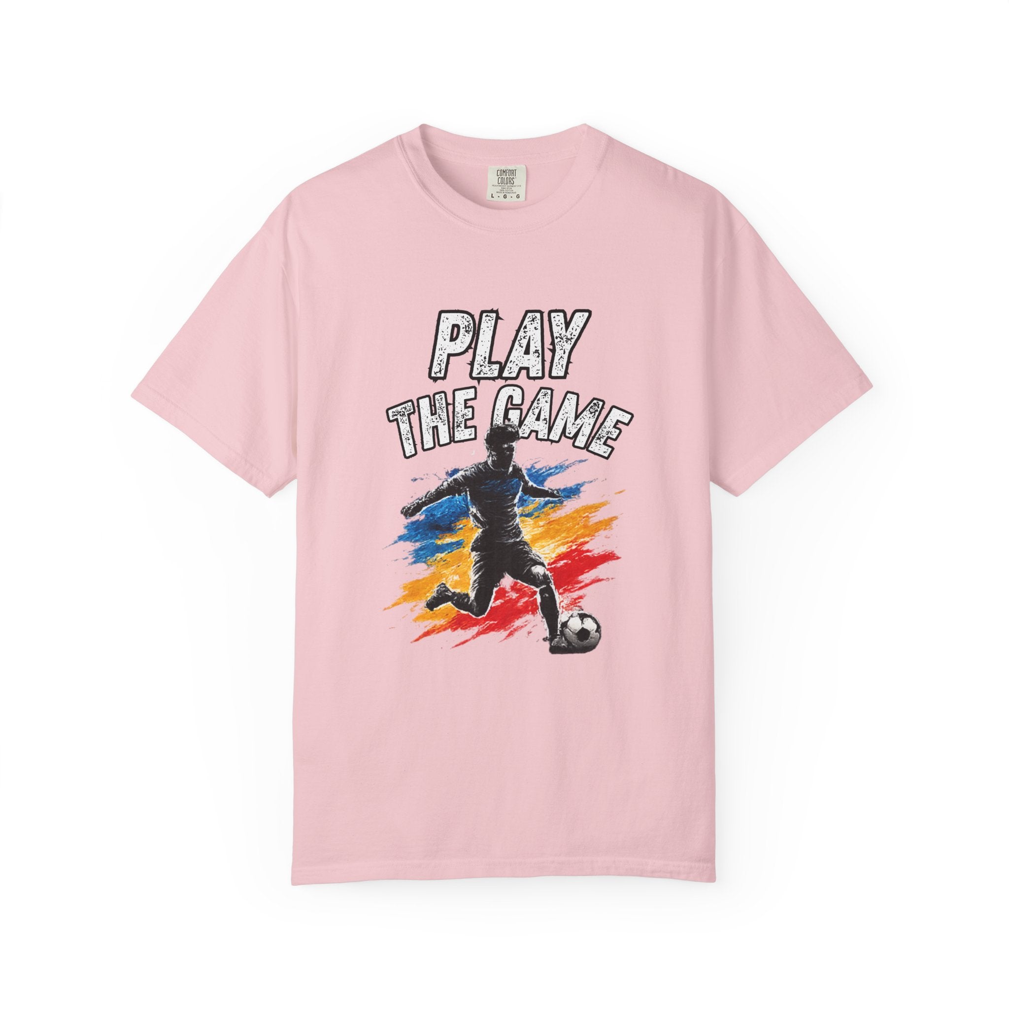 A light pink short-sleeve crewneck t-shirt featuring a graphic print of a soccer player kicking a ball with the text 'PLAY THE GAME' above them, set against a plain white background.