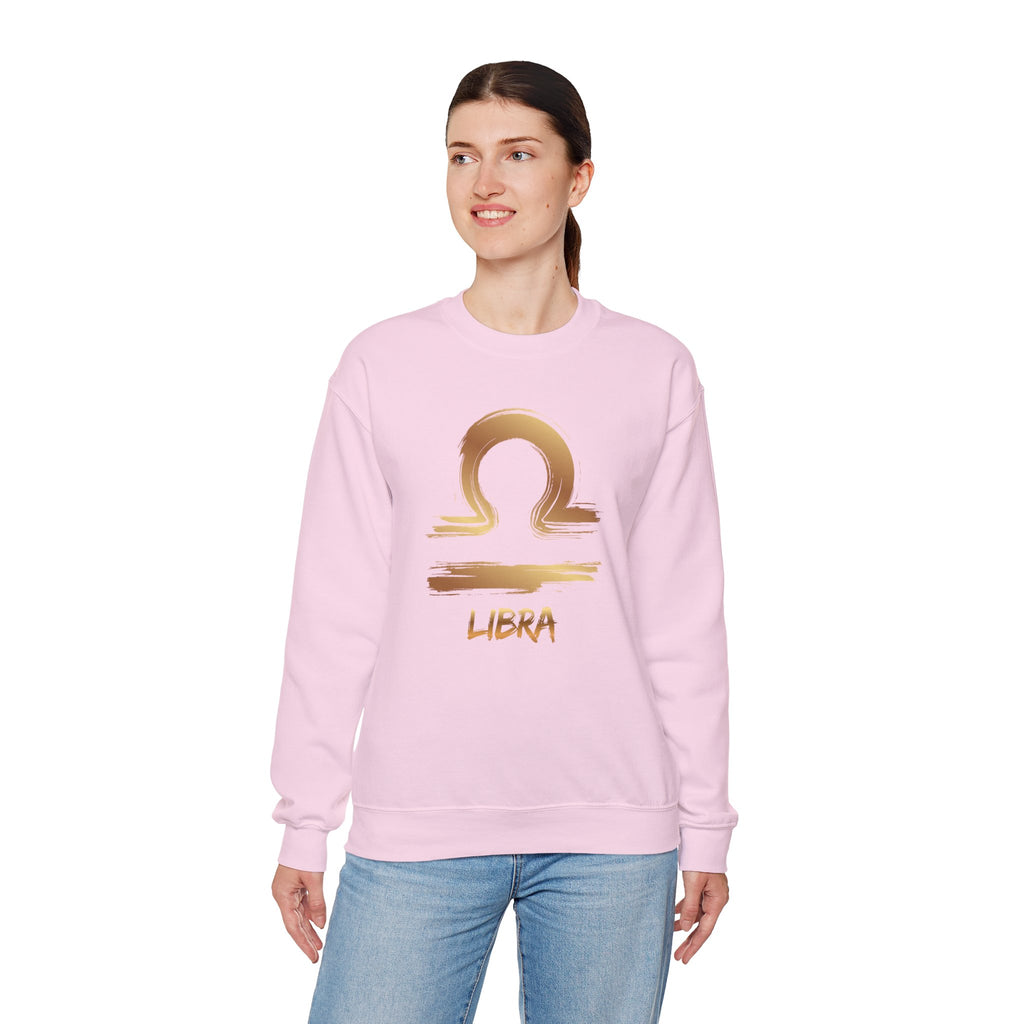 Person wearing a pink sweatshirt with a gold Libra zodiac symbol on a white background