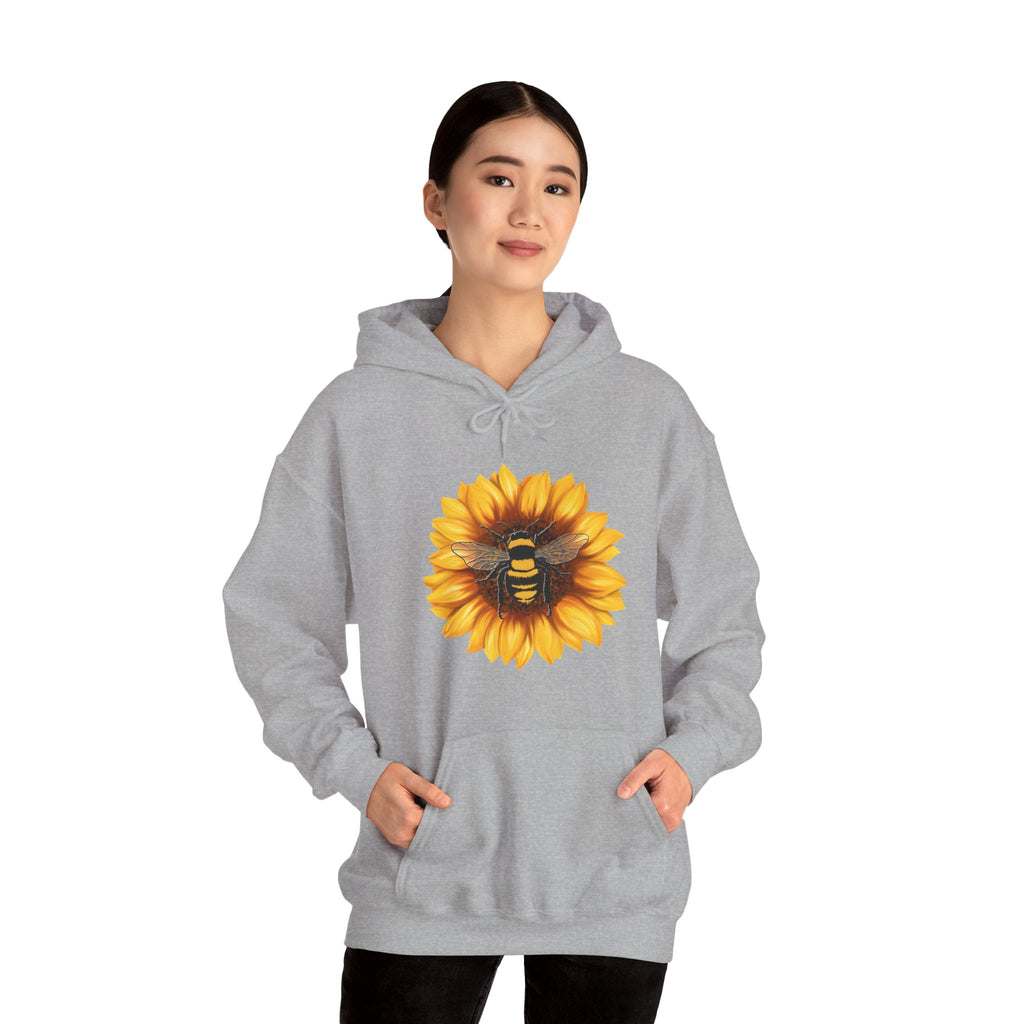 Person wearing a gray hoodie with a sunflower and bee design on a white background