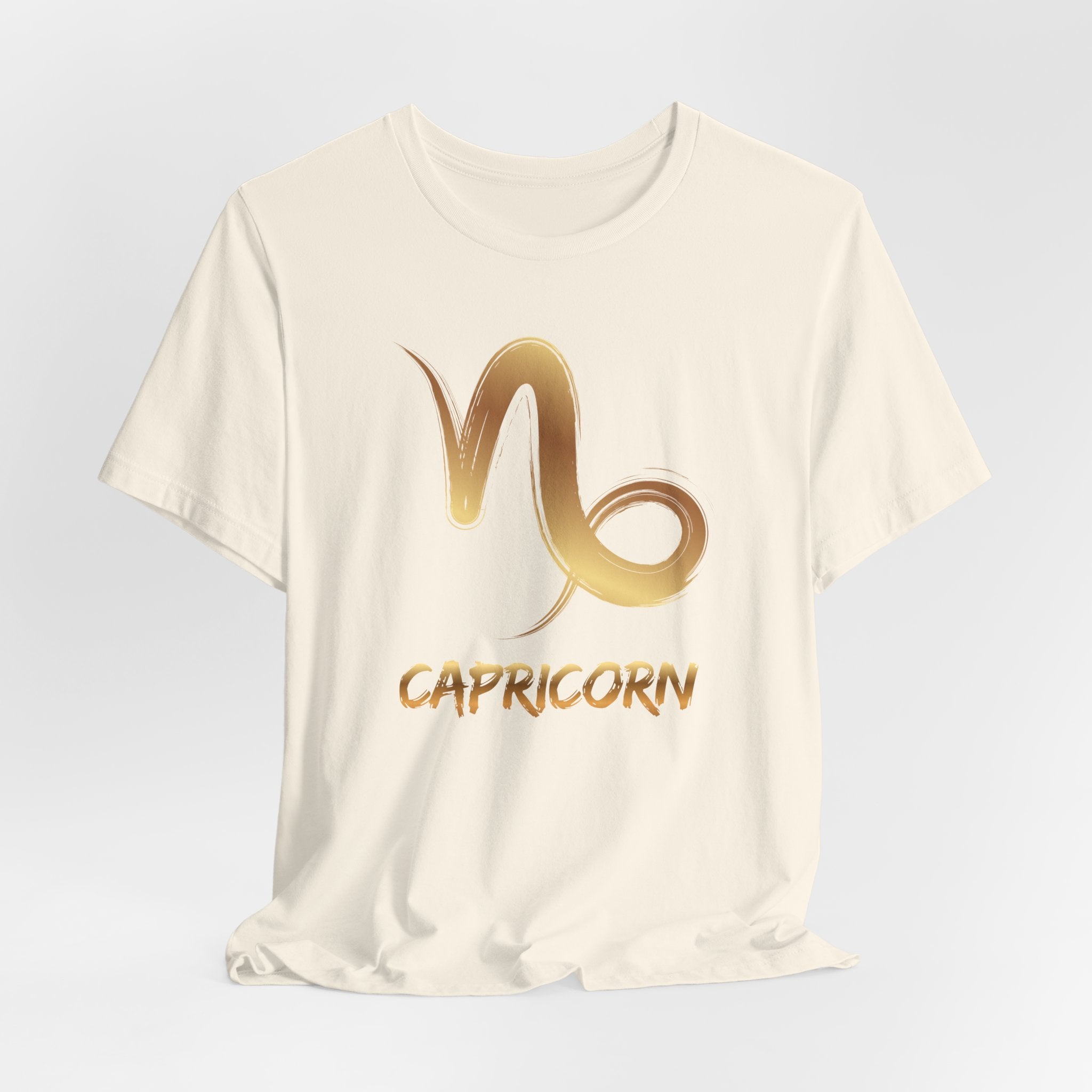White t-shirt with gold Capricorn zodiac symbol on a light gray background