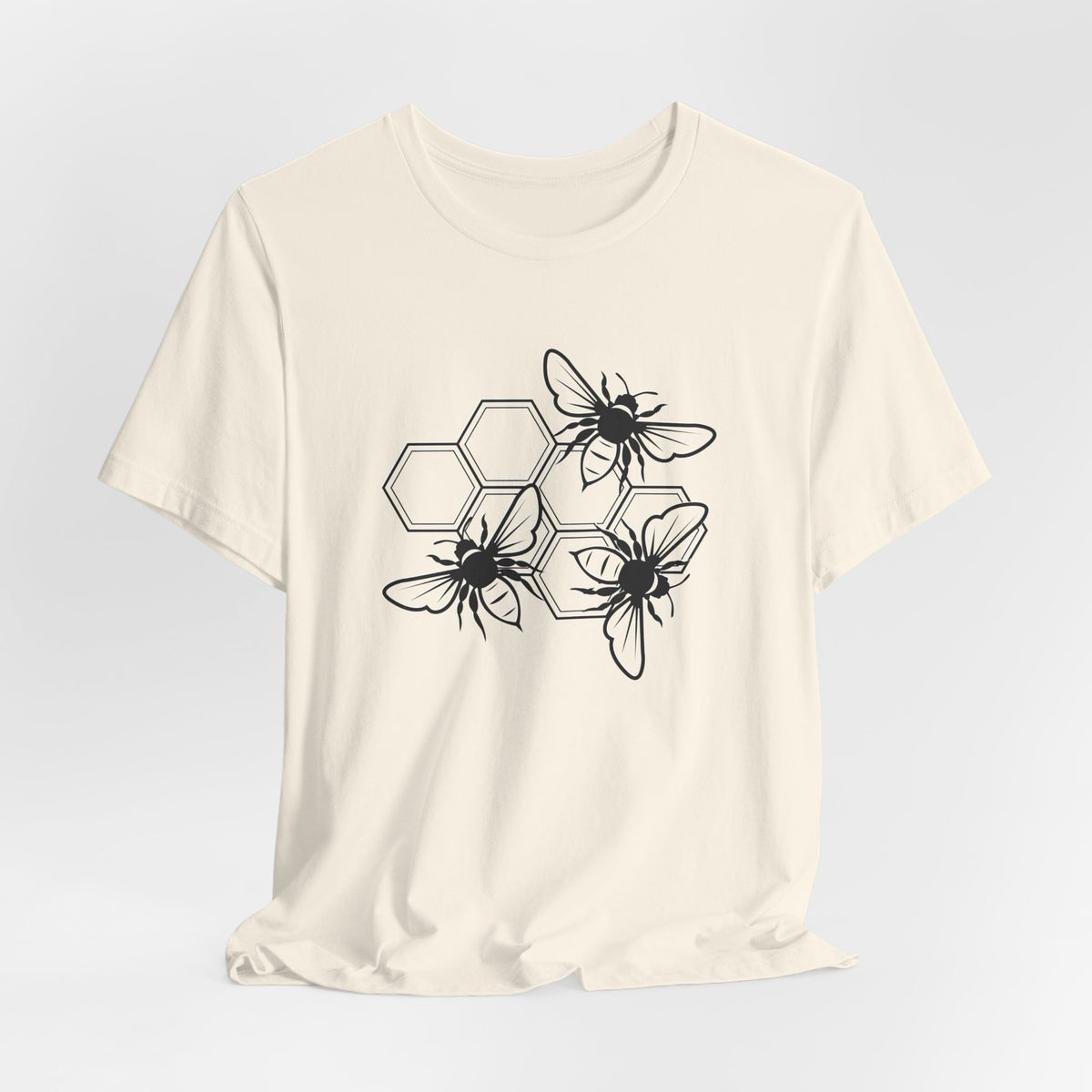 White t-shirt with black bee and hexagon pattern on a light gray background